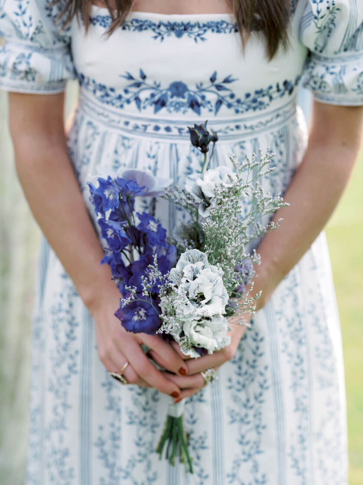 Close-up shot of a small, blue and white flower bouquet held by a bridesmaid, at The Ausable Club, NY. Image by Jenny Fu Studio.
