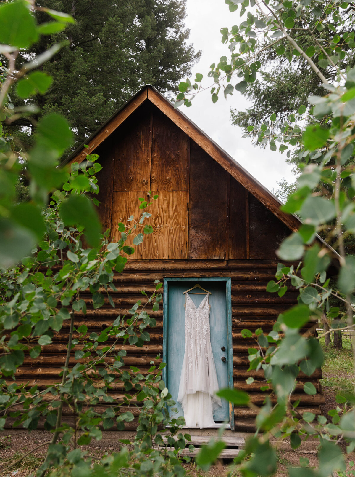 Wedding gown hanging from door at rustic cabin