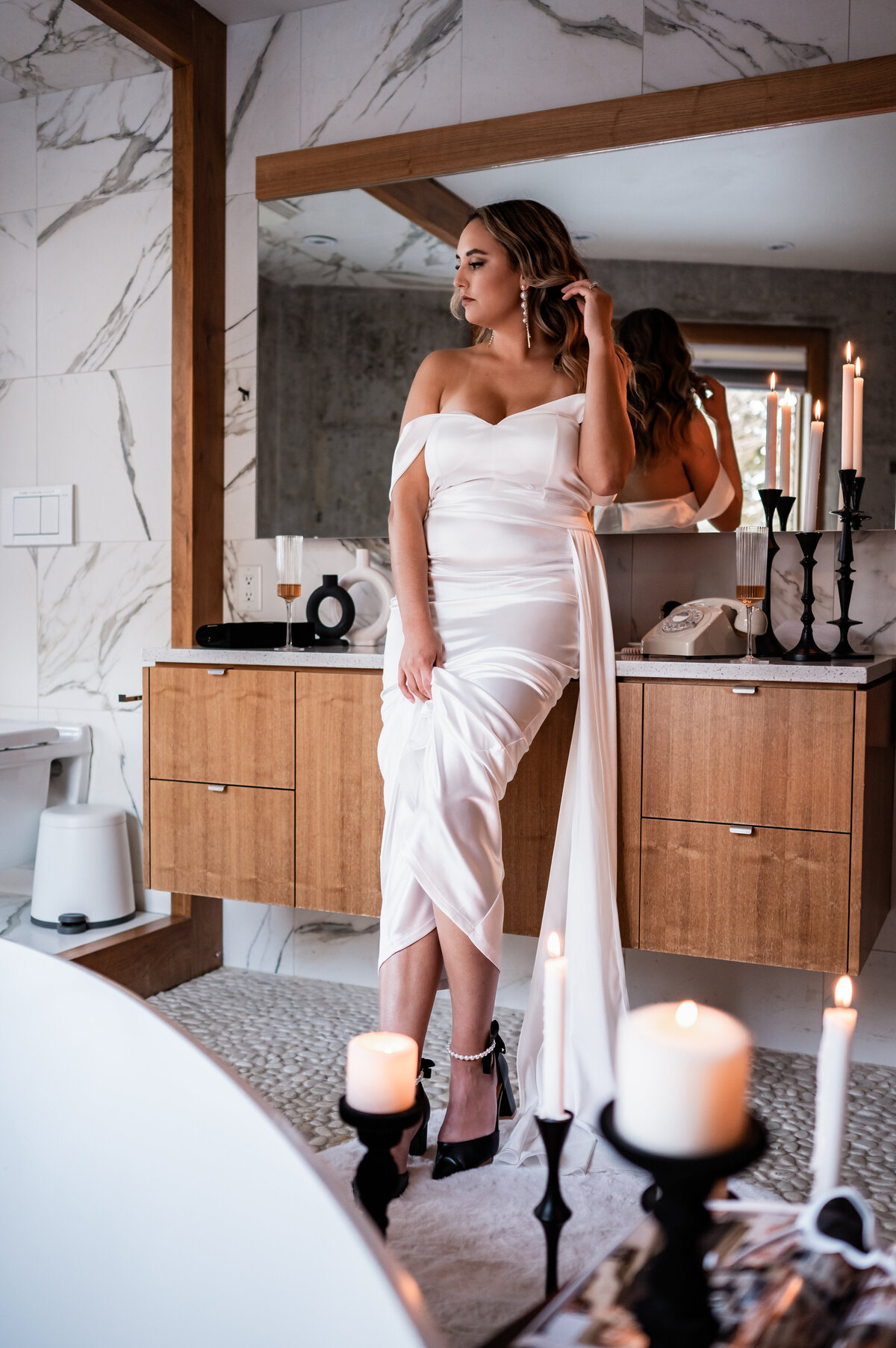 bride getting ready for her wedding in front of a large mirror showing off her earrings
