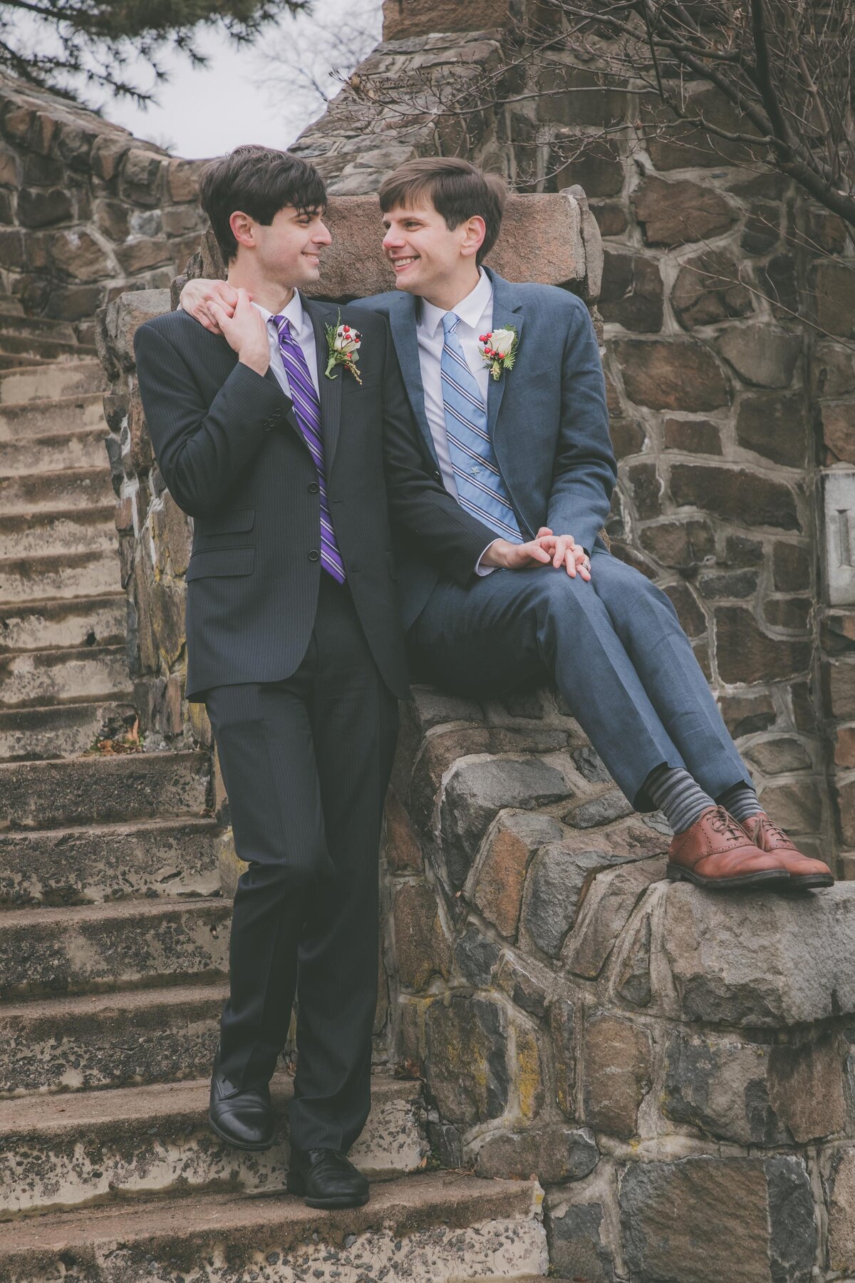 A gay couple poses on a stone staircase.