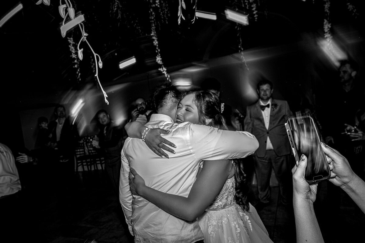 The bride and groom share an intimate embrace on the dancefloor at Casa Real, surrounded by soft lighting and a romantic atmosphere, capturing the love and joy of their special day.