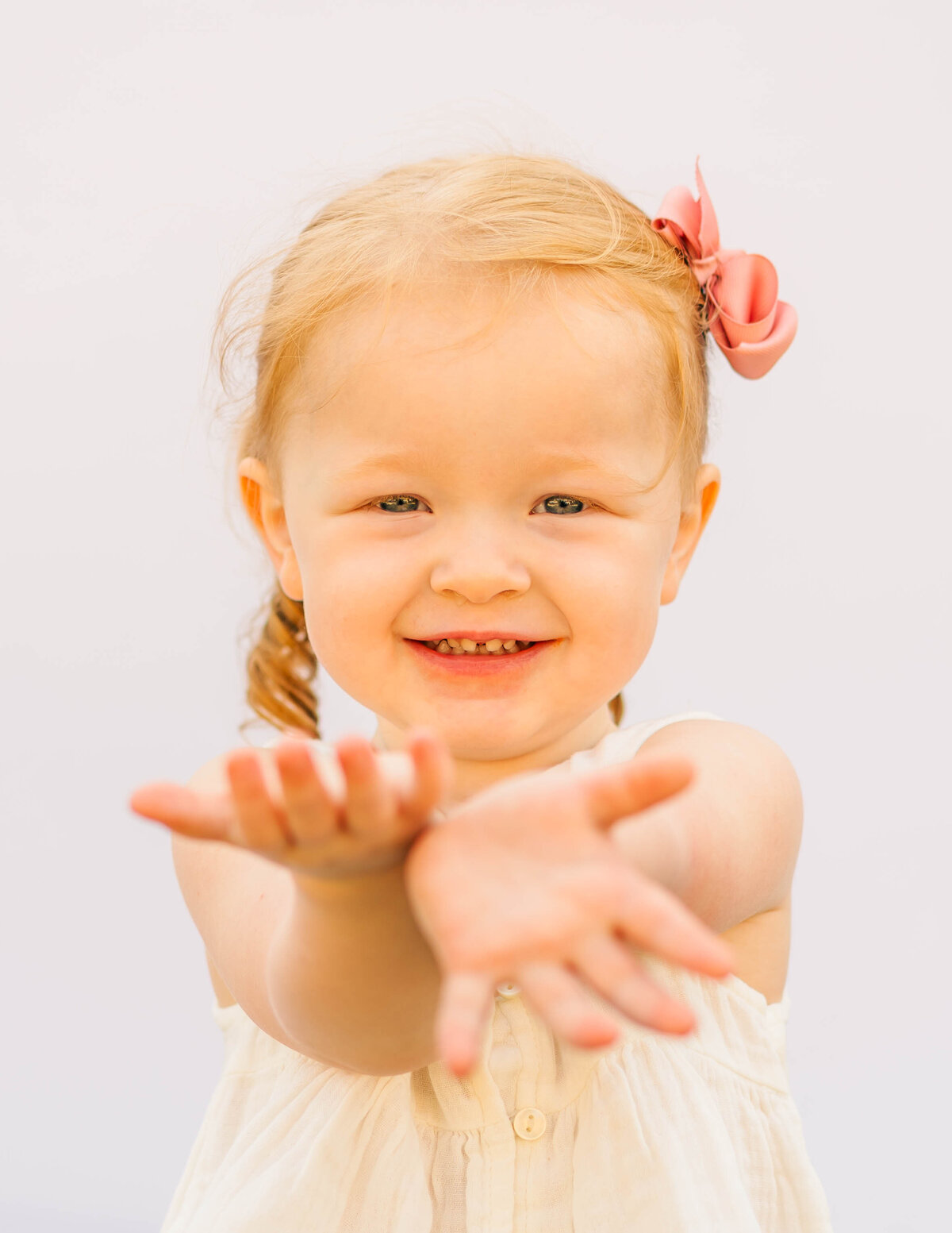 Natural portrait of toddler girl with relaxed pose and white backdrop