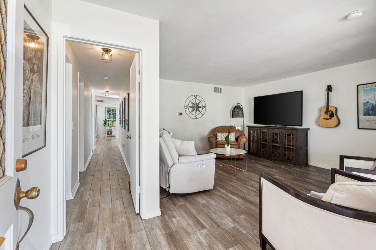 Entrance to home with living room seating on the right side and a hallway to the left. 