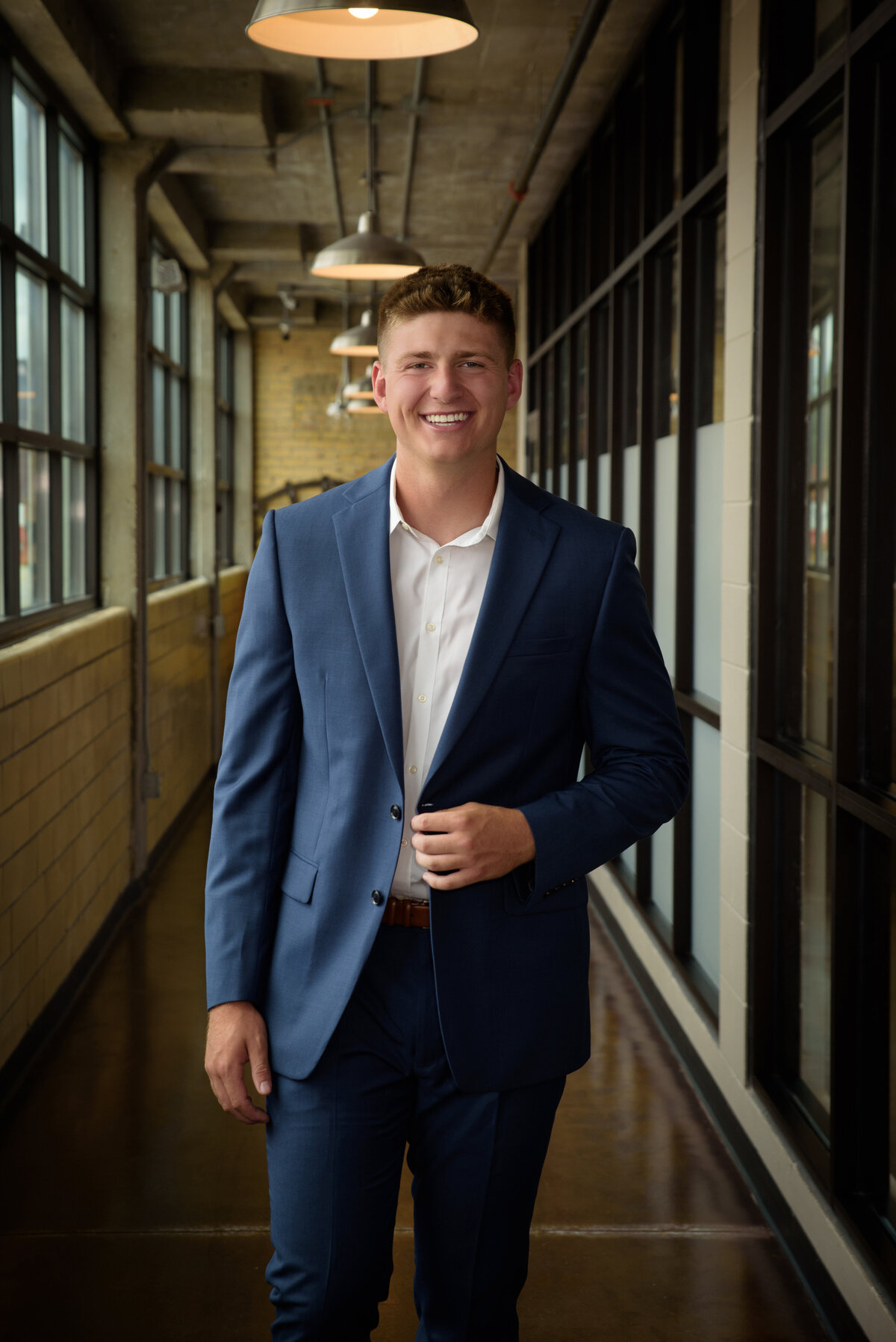 De Pere High School senior boy wearing a blue suit with white shirt standing in urban setting in Downtown Green Bay, Wisconsin