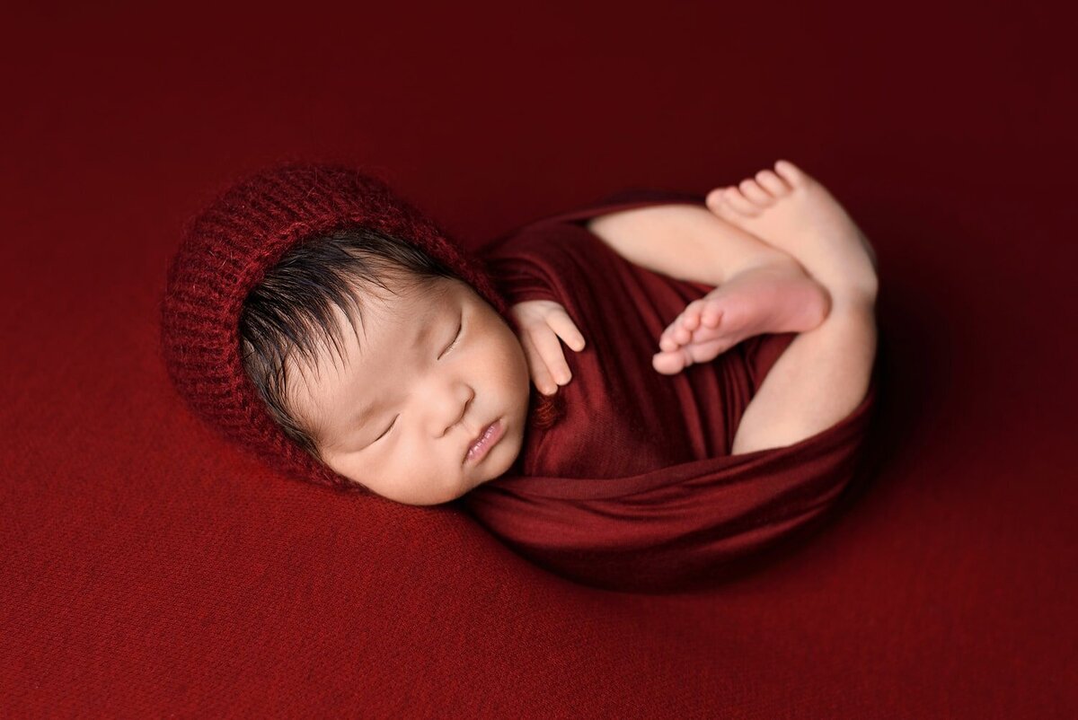 Asian newborn boy wrapped in red for Richmond newborn home photo session
