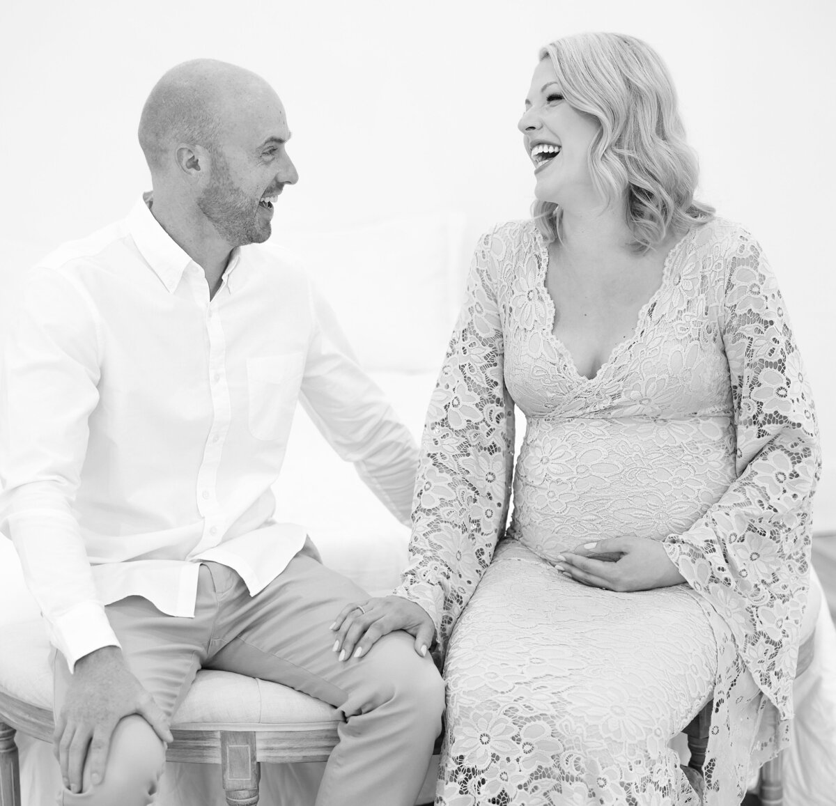 husband and wife smiling and laughing during asheville maternity session