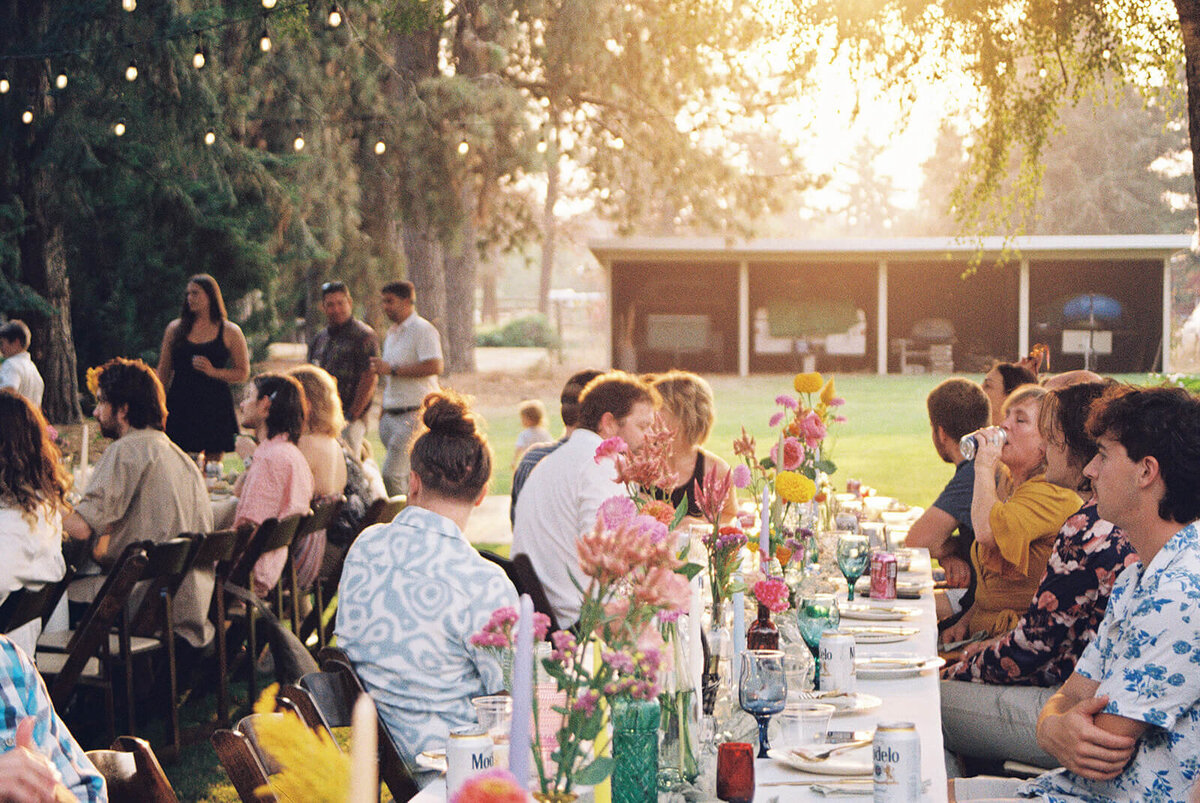 Wedding guests seated at tables at backyard wedding. 