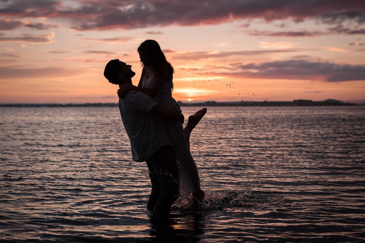 A silhouette of a couple in the sea at sunset on Sandbanks beach