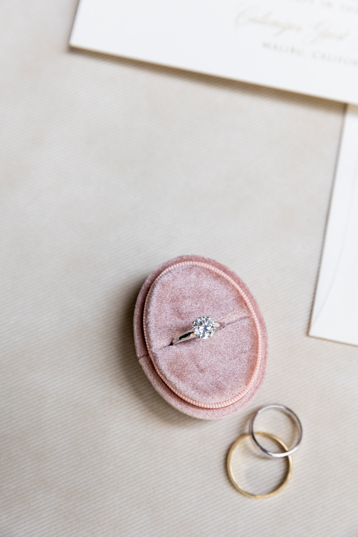 An engagement ring in a box with wedding bands next to it