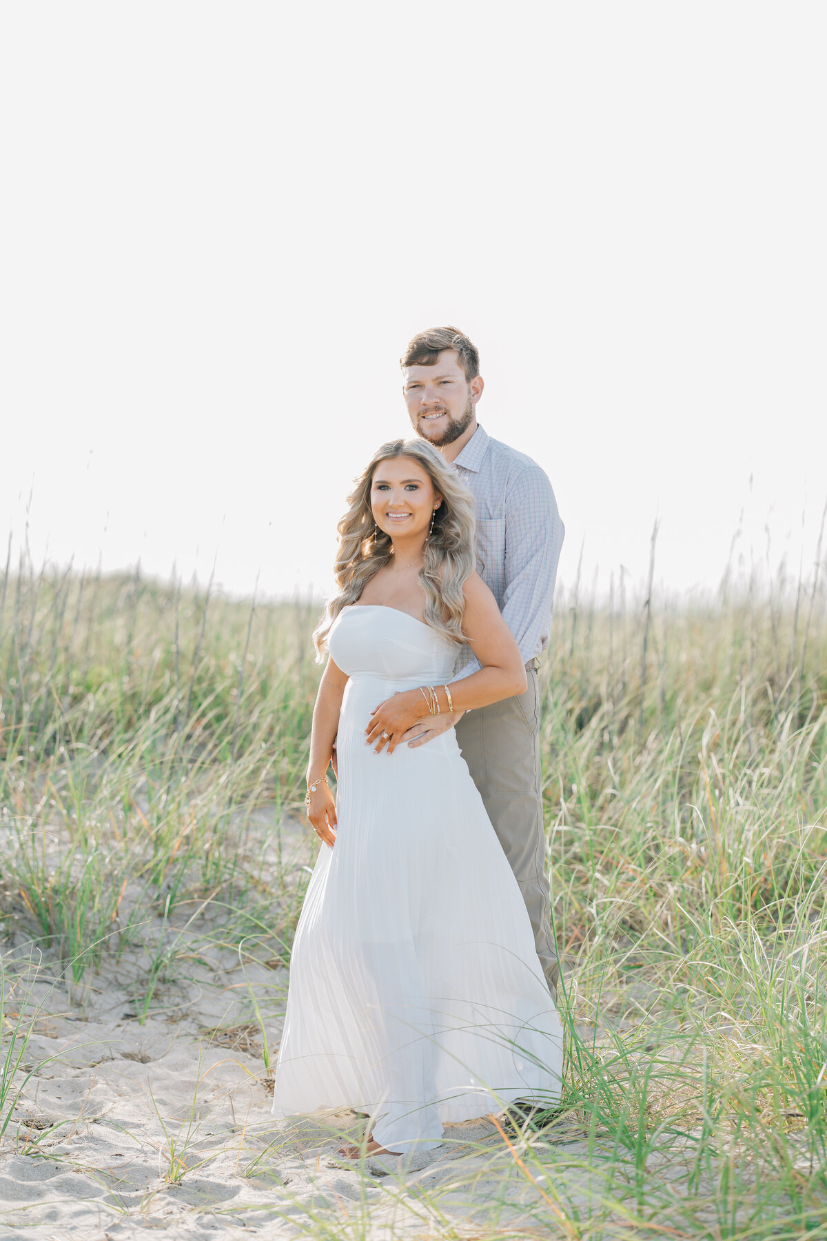 an engaged couple posing together on the beach