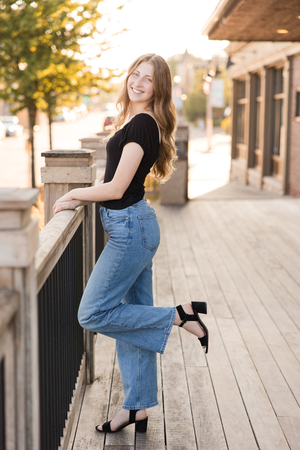Senior girl standing along a railing smiling at the camera