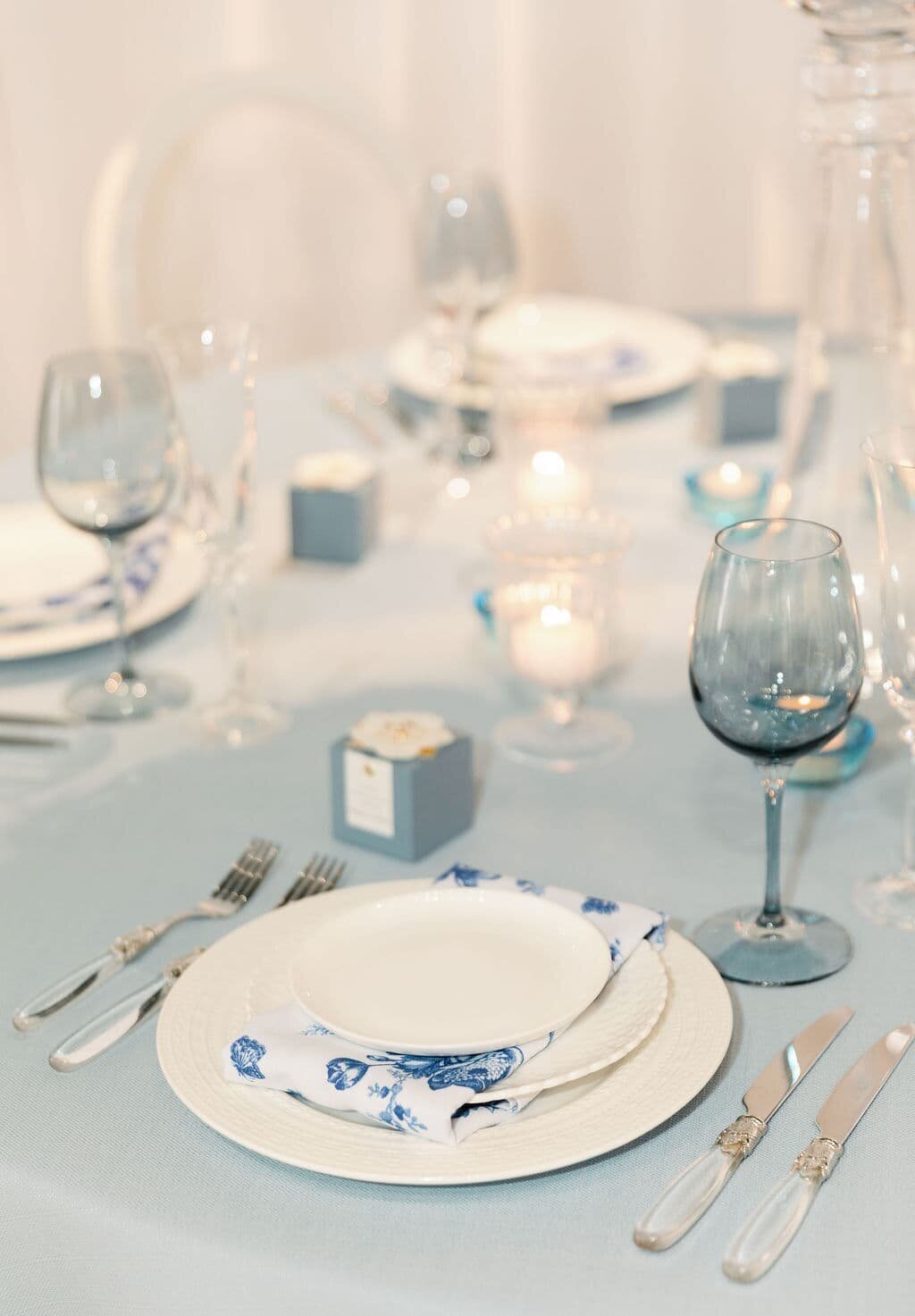 Tasteful Maryland wedding table decor featuring blue accents, ambient candlelight, and a beautifully set place for guests, highlighting attention to detail in floral and event design.