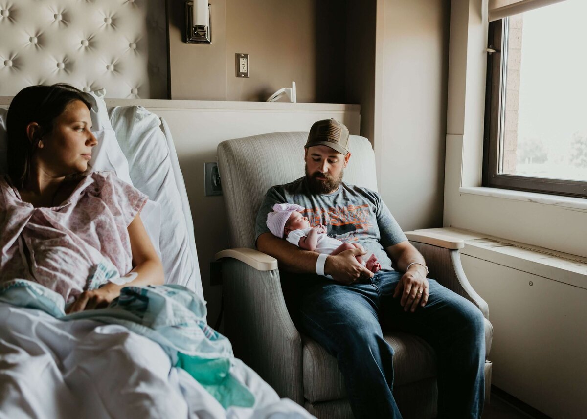 A man and woman sitting in a hospital room with their newborn baby.