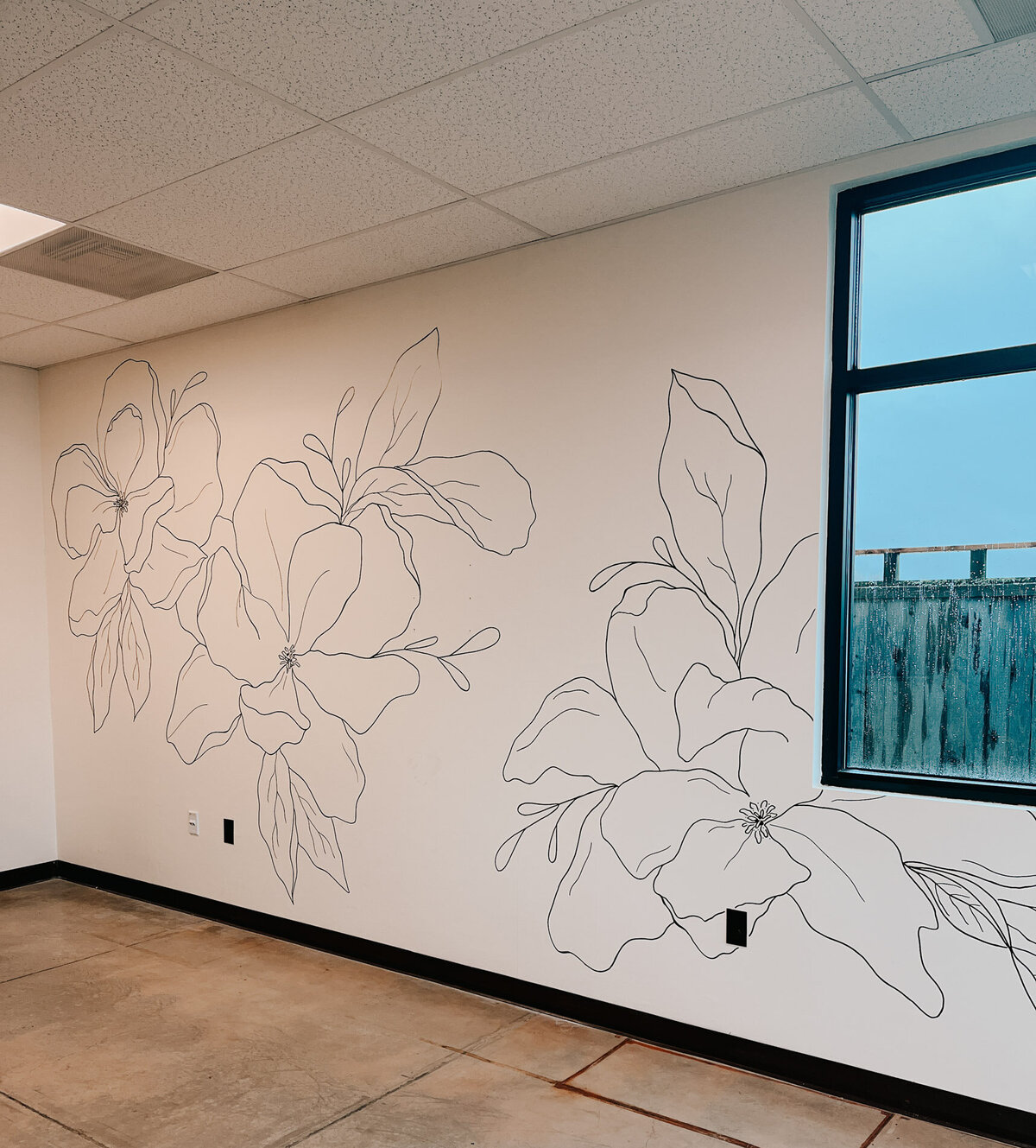 A salon wall in white with large black modern florals drawn on it representing full service design and calligraphy by Life in Letters.