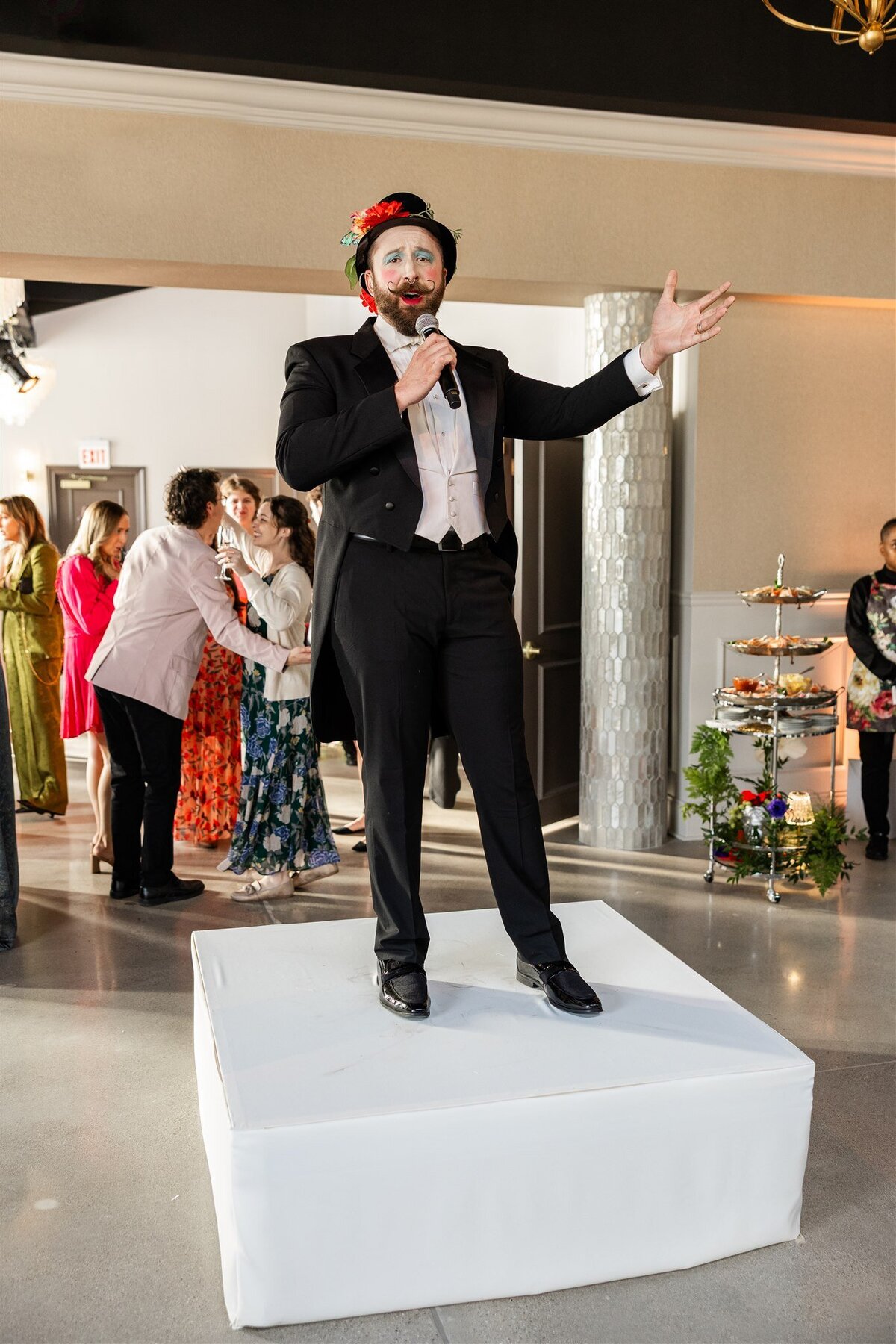 Live entertainment during cocktail hour at an event, featuring a musician performing while guests mingle with drinks in hand, surrounded by elegant decor and ambient lighting