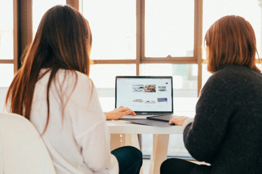 two women sitting on a desk reviewing website designed by ATamez Design