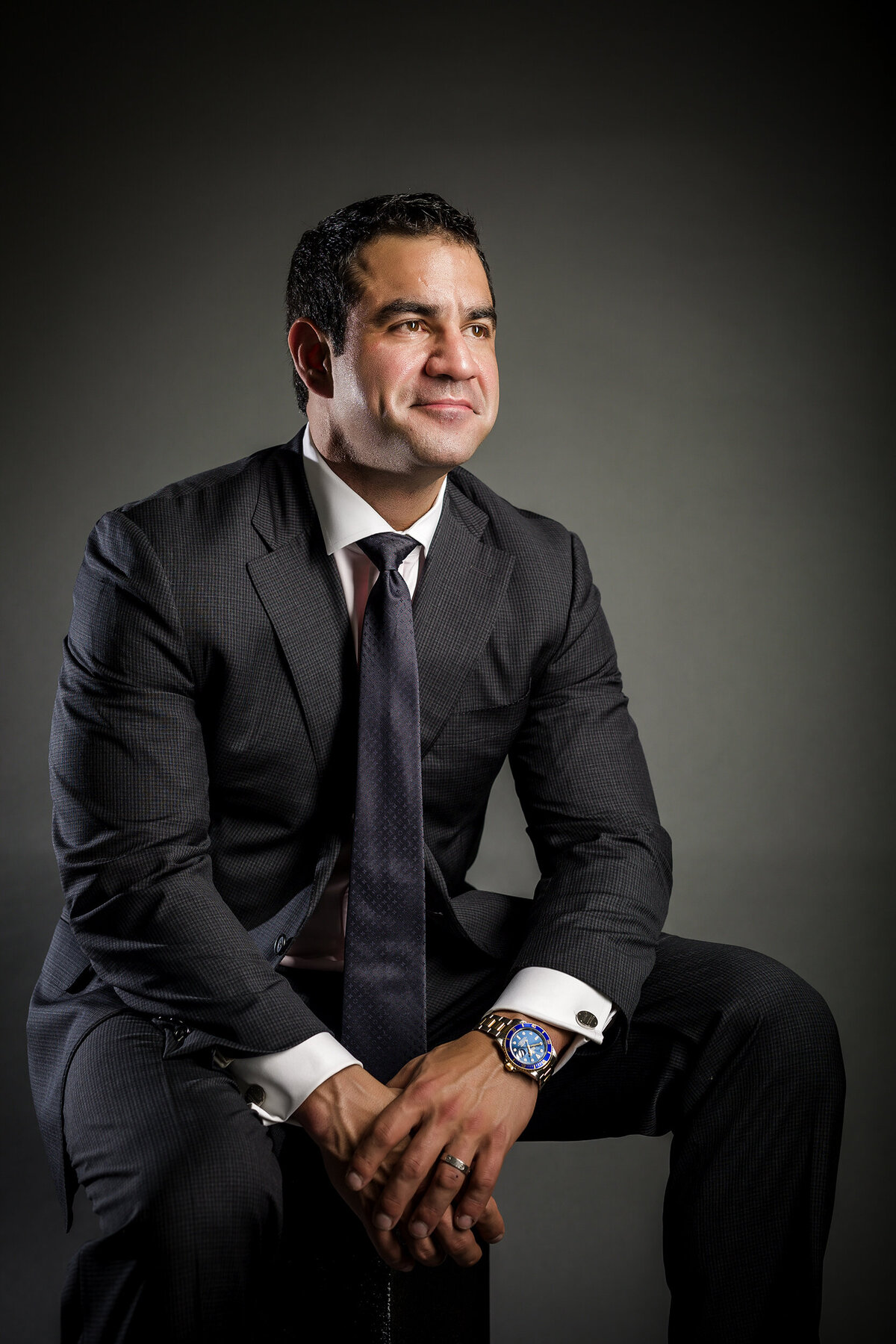 Headshot image of a man wearing a dark suit looking off