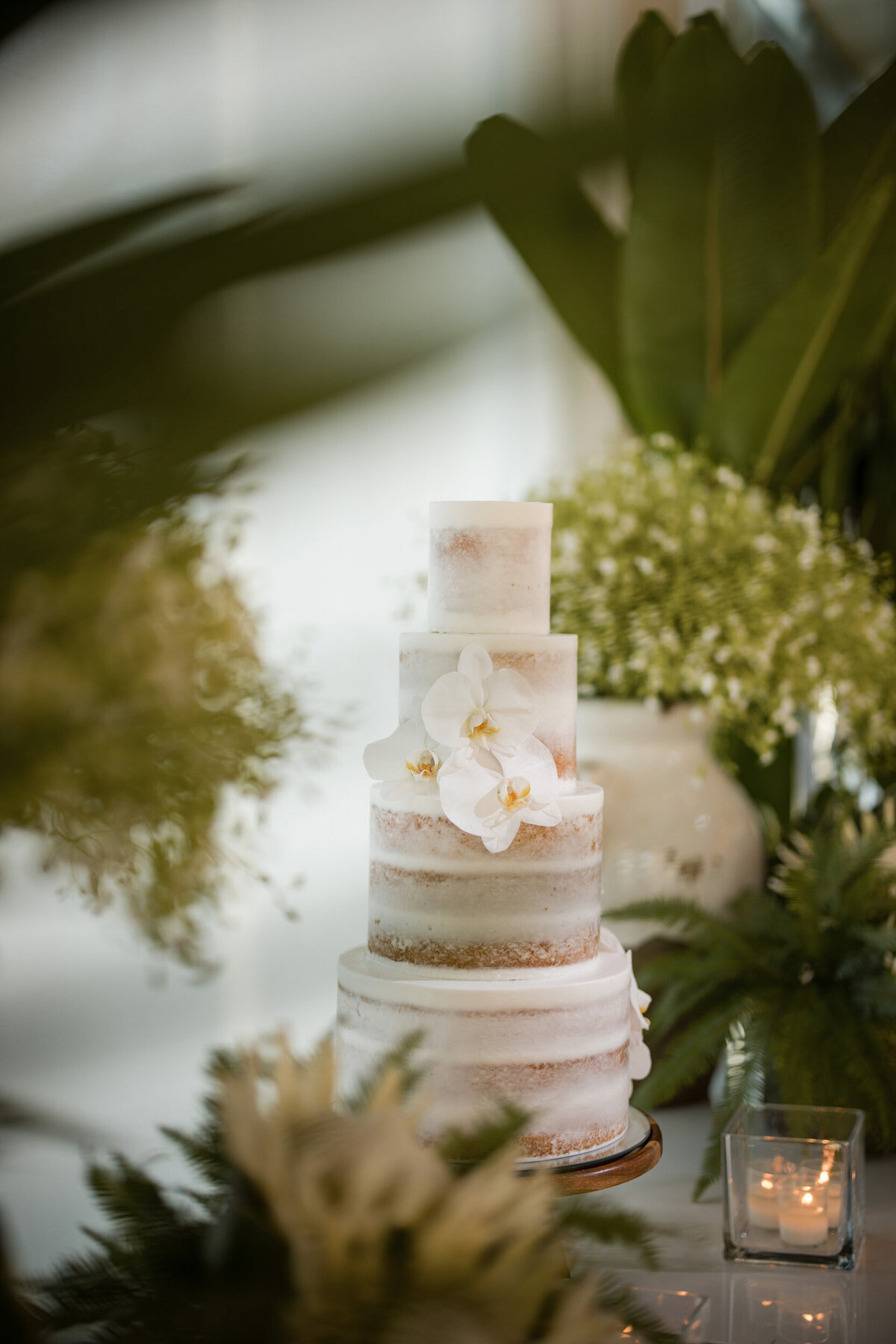 An all white wedding cake with green leaves  at a destination wedding in Puerto Rico