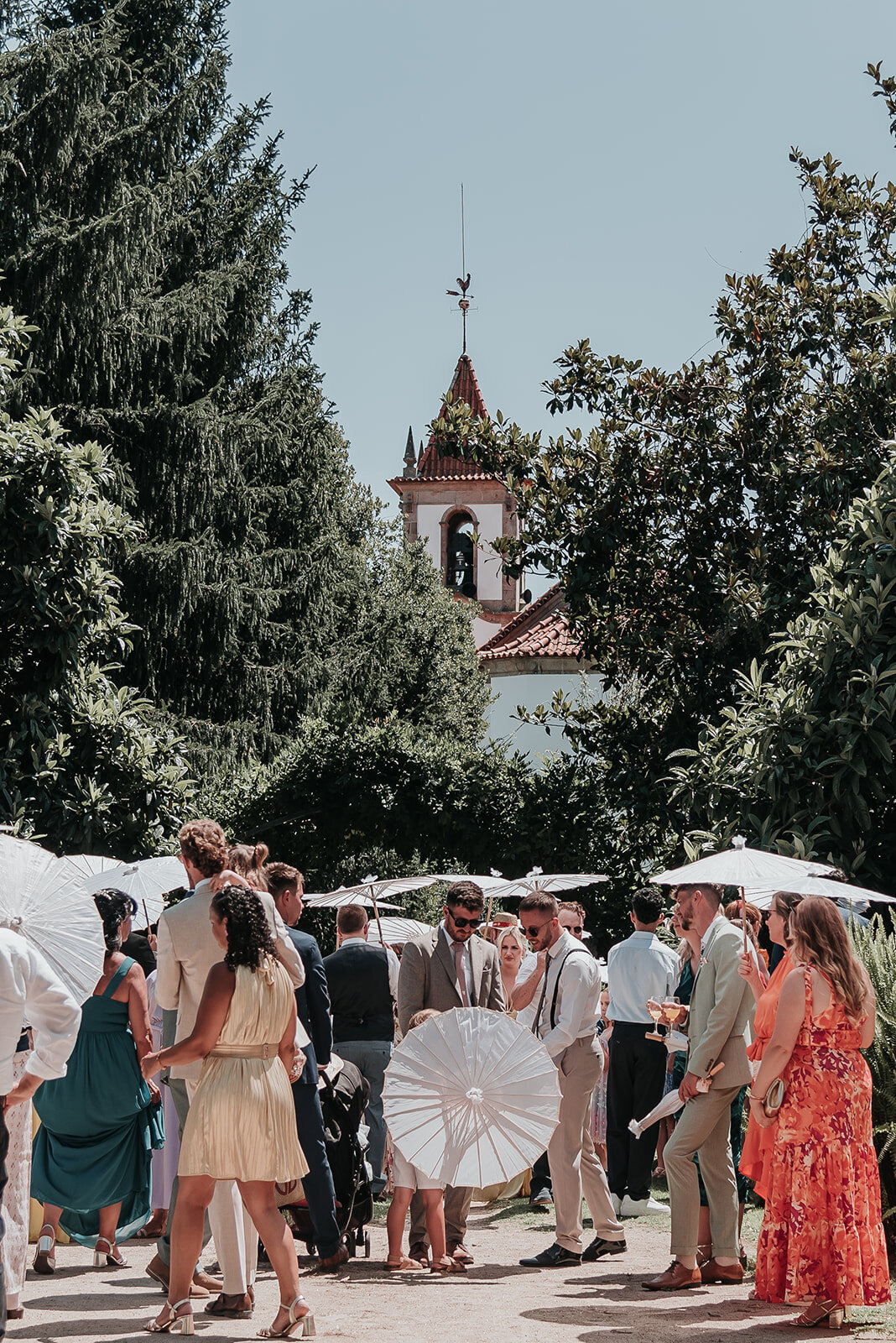 Guests with white parasols arriving at a sunny wedding in Ponte De Lima Portgual