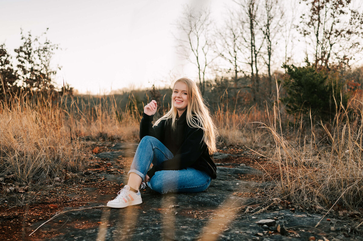 senior girl sitting in field captured by Springfield MO senior photographer