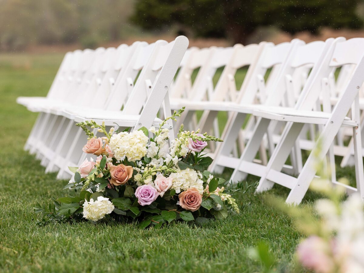 Ceremony aisle flower arrangements at a vineyard wedding.