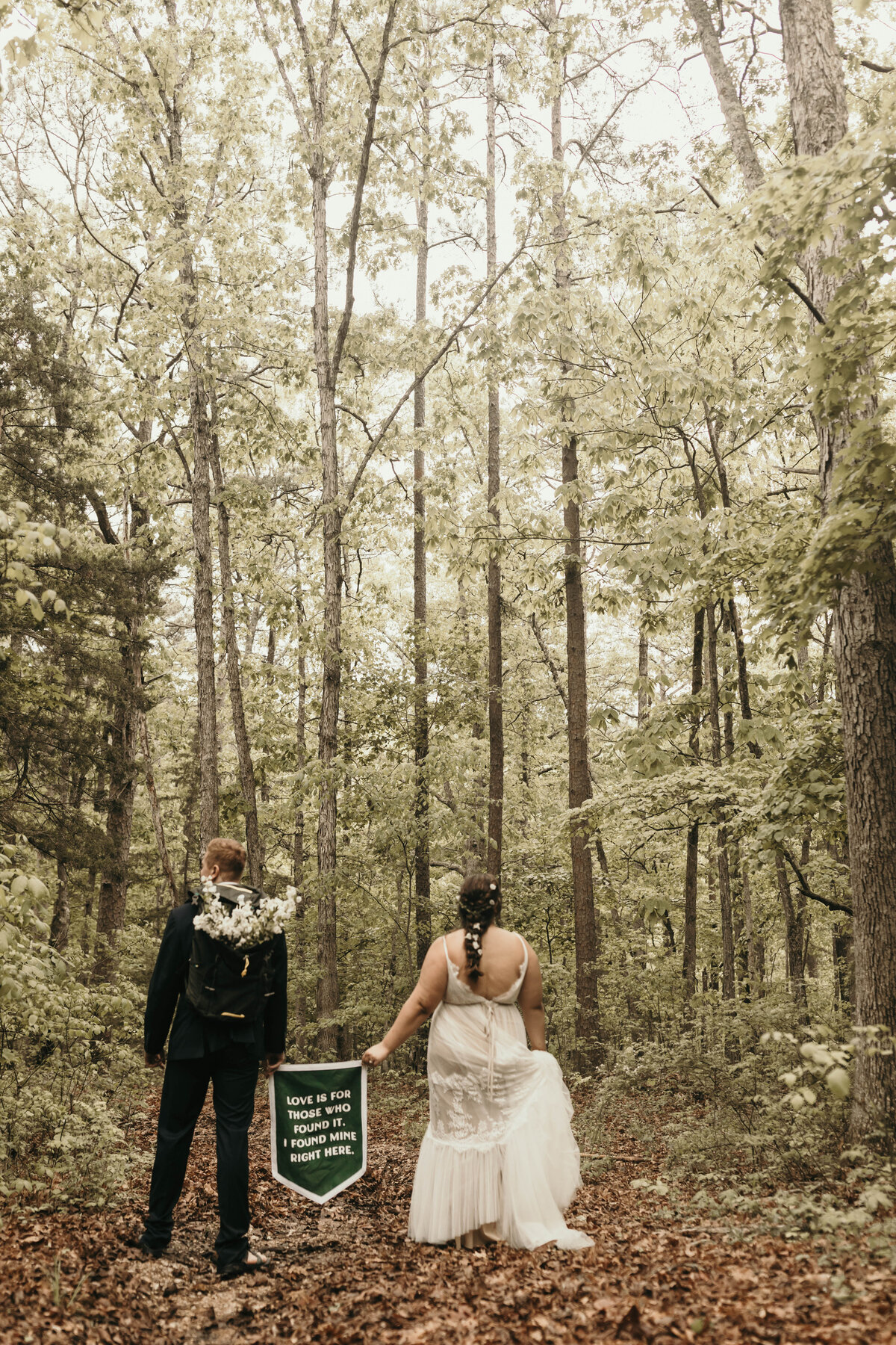 couple holding banner, walking through the woods.