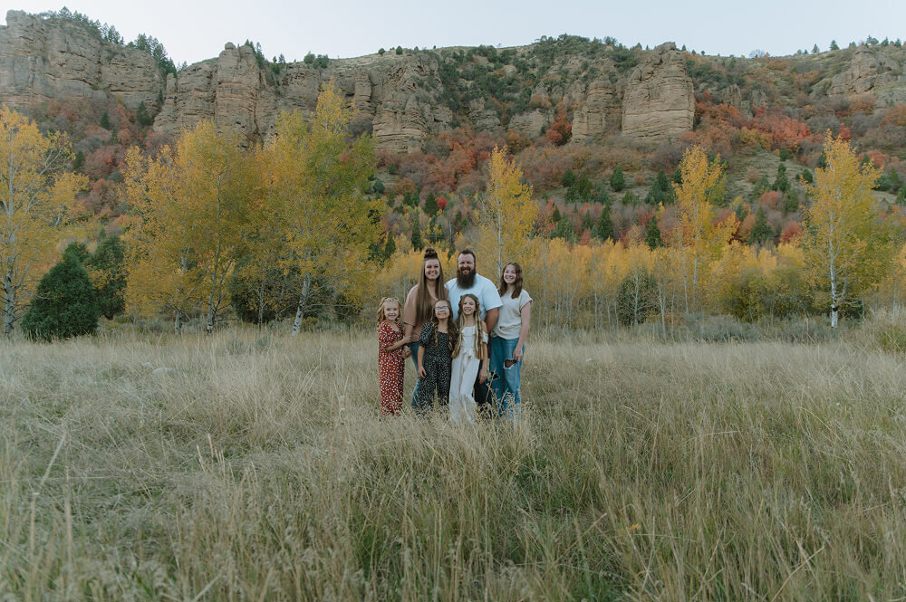 A family with 4 daughters and a mom and dad smile for a classic family photo outside in eastern Idaho. 