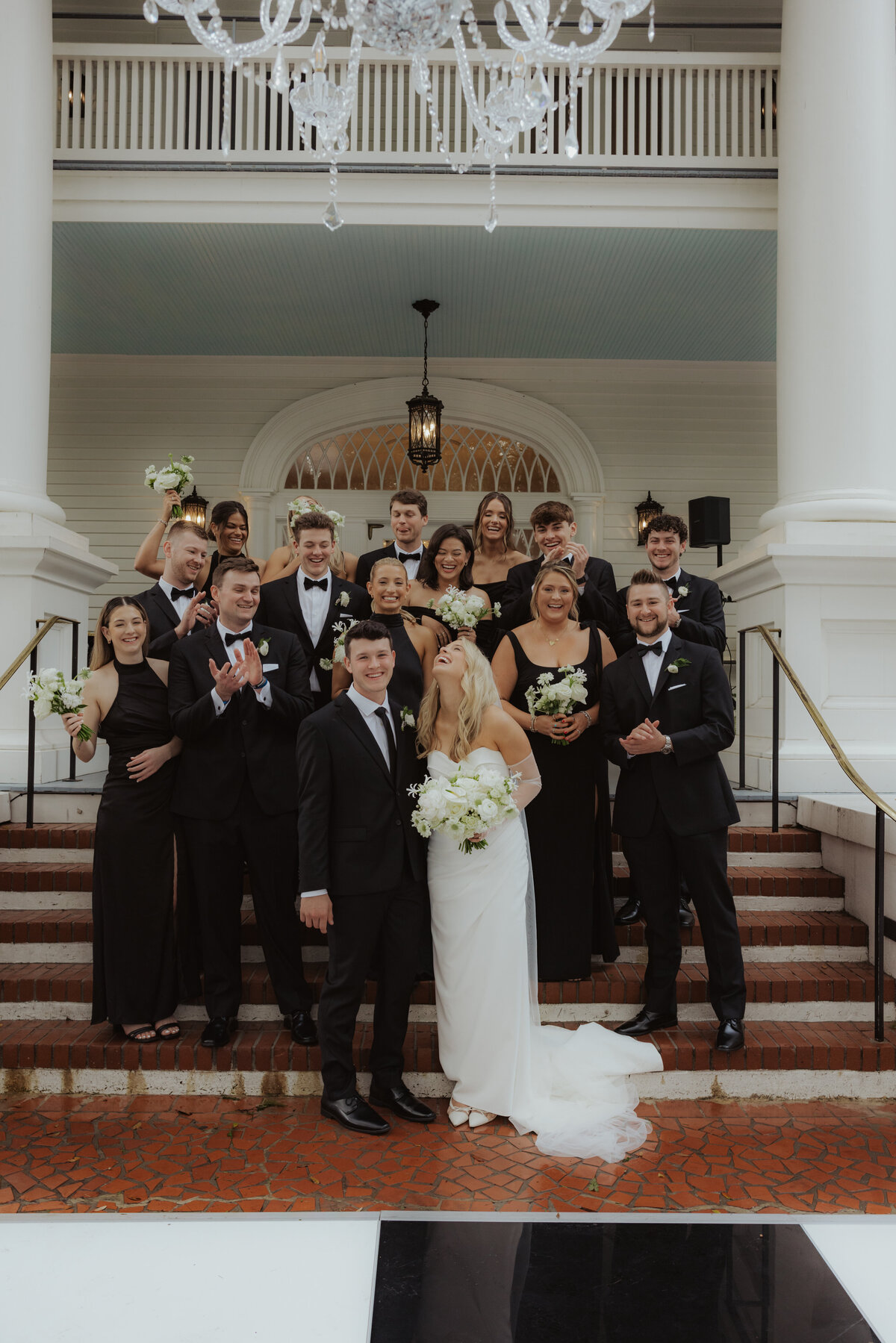 Couple framed between two white columns with wedding party

