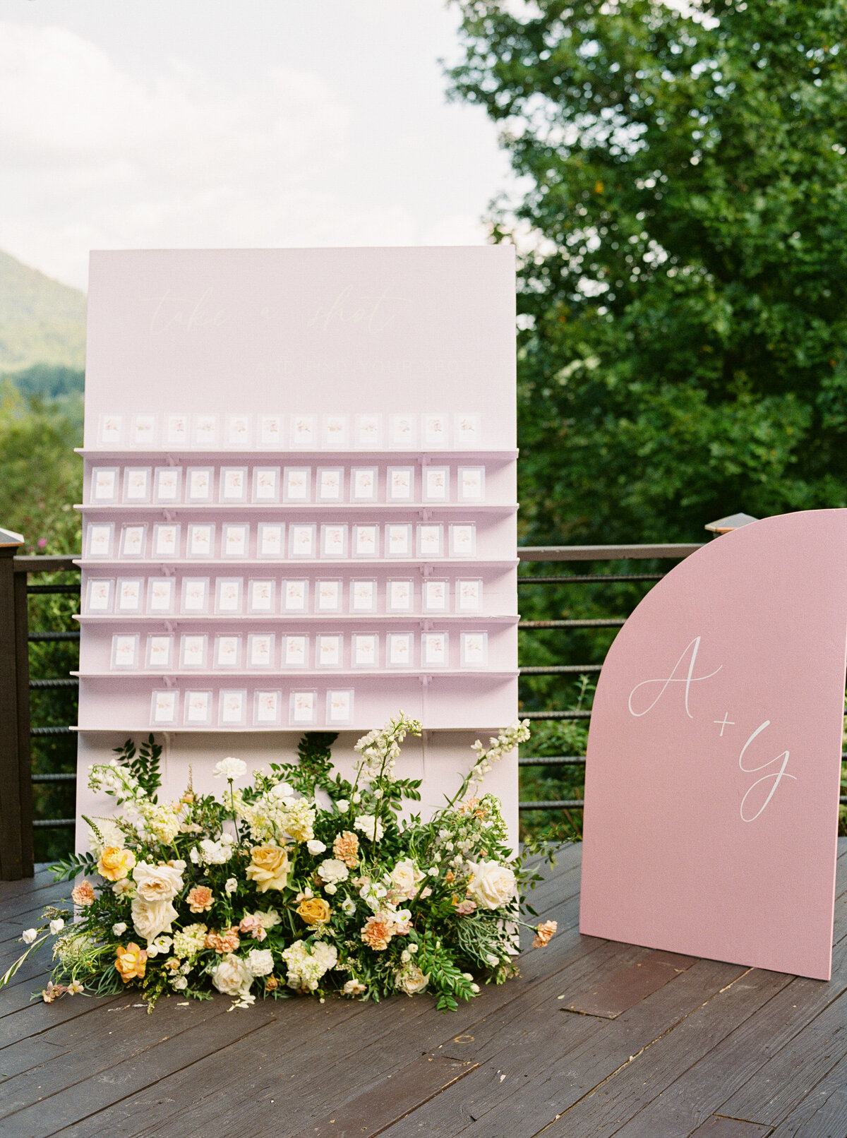 Modern wedding escort display and shot wall with floral accents at Castle Ladyhawke—“Take a shot and find your seat.