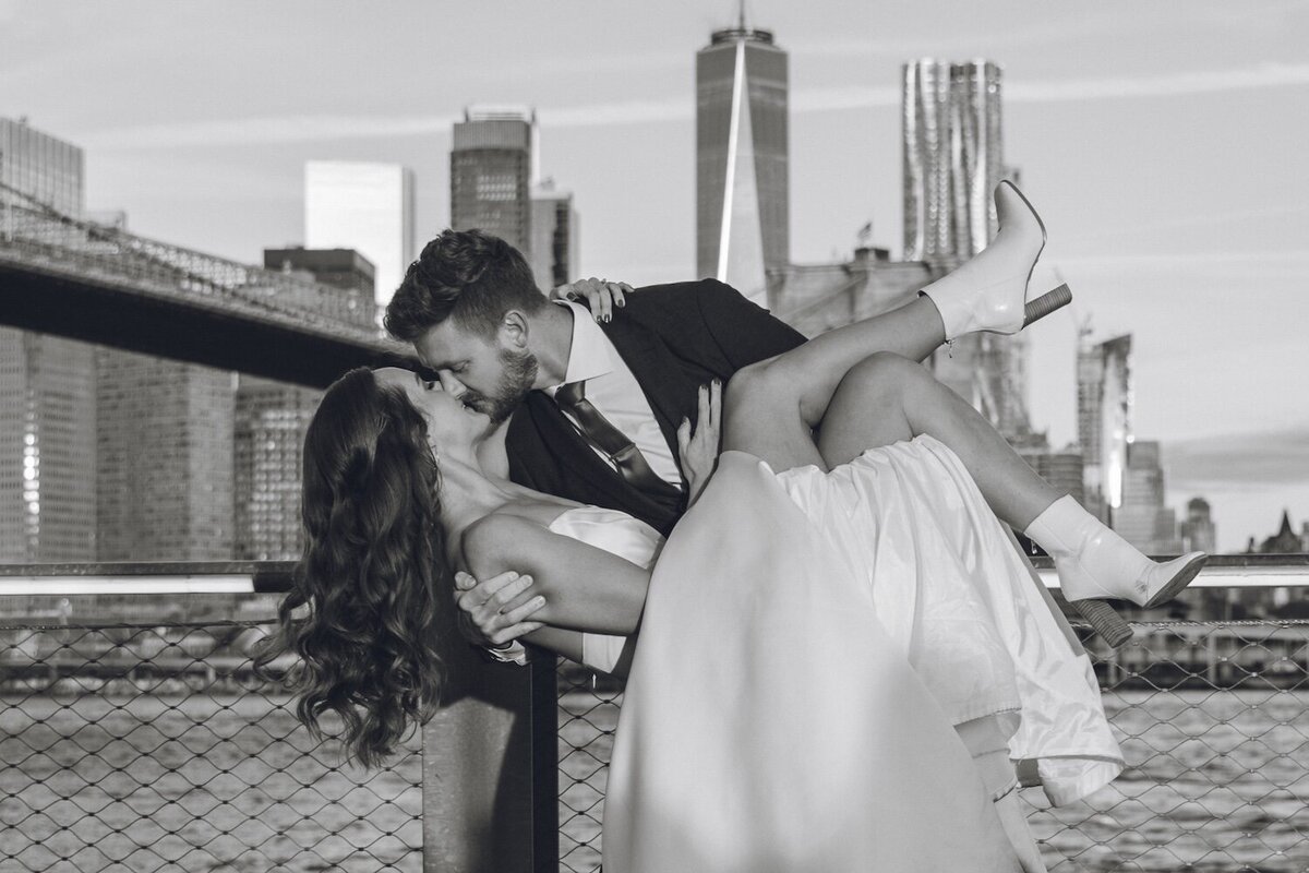 Groom dipping bride with NYC skyline in background