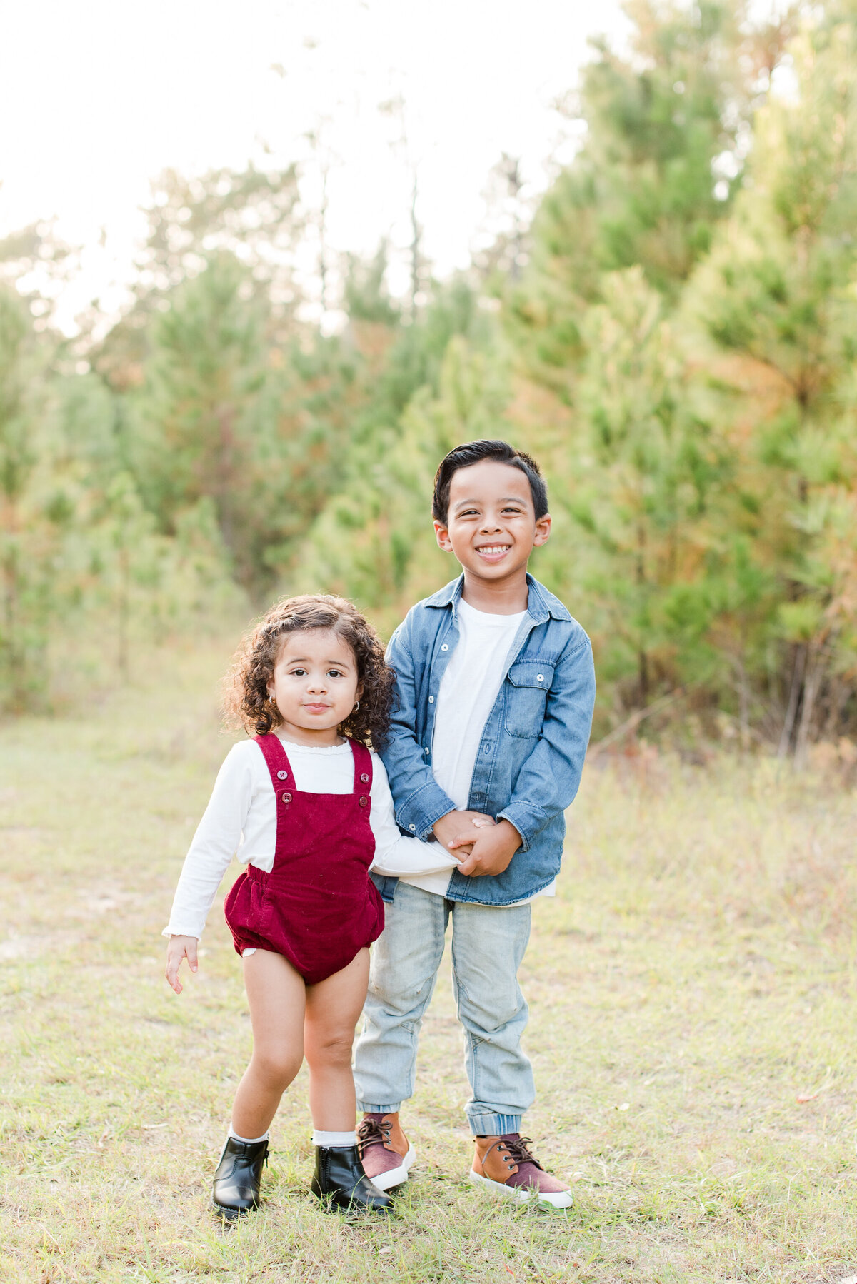 siblings boy and girl holding hands burgindy  romper and denim jacket