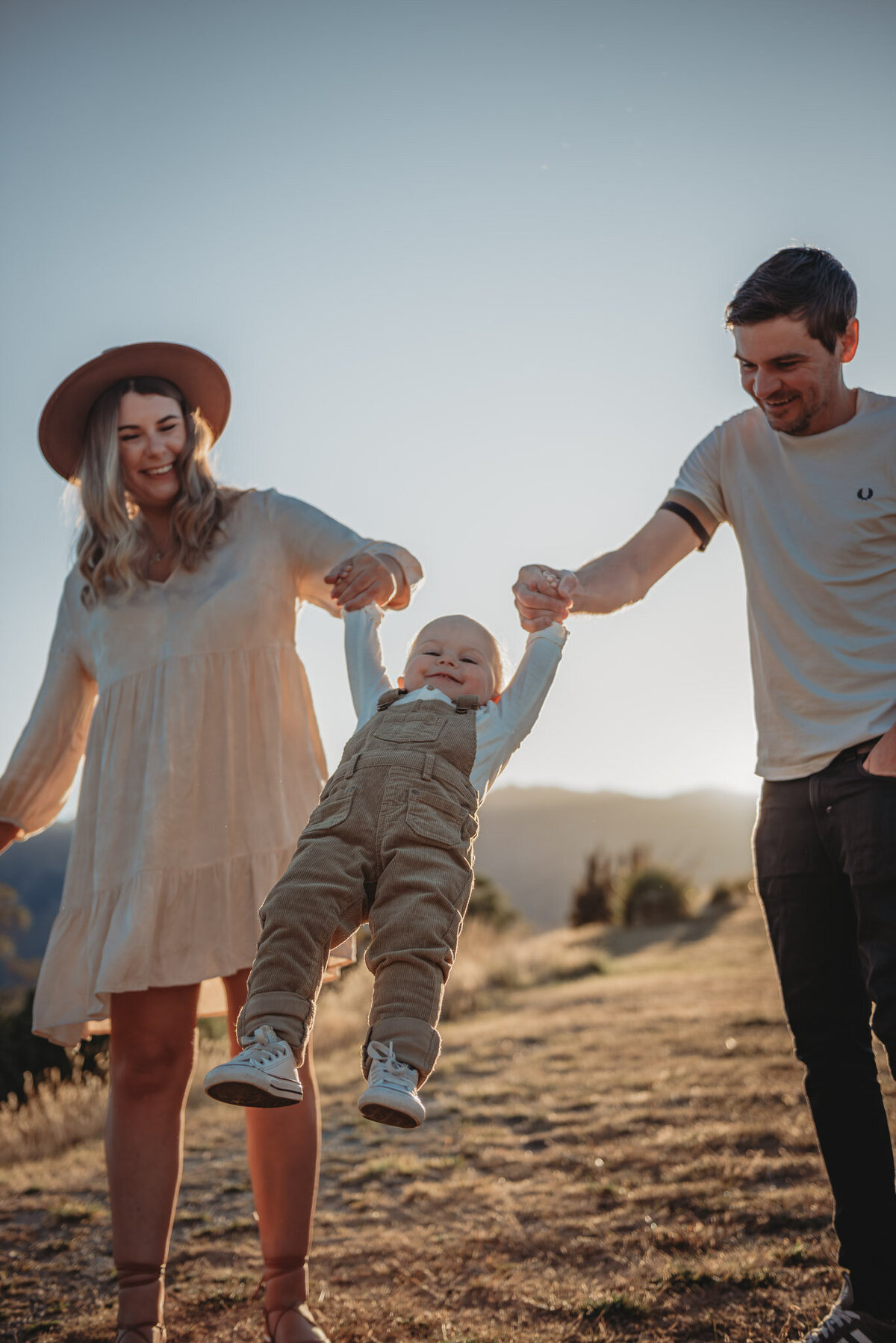 a boy swinging with mum and dad during a family photoshoot captured by Bie in Wanaka