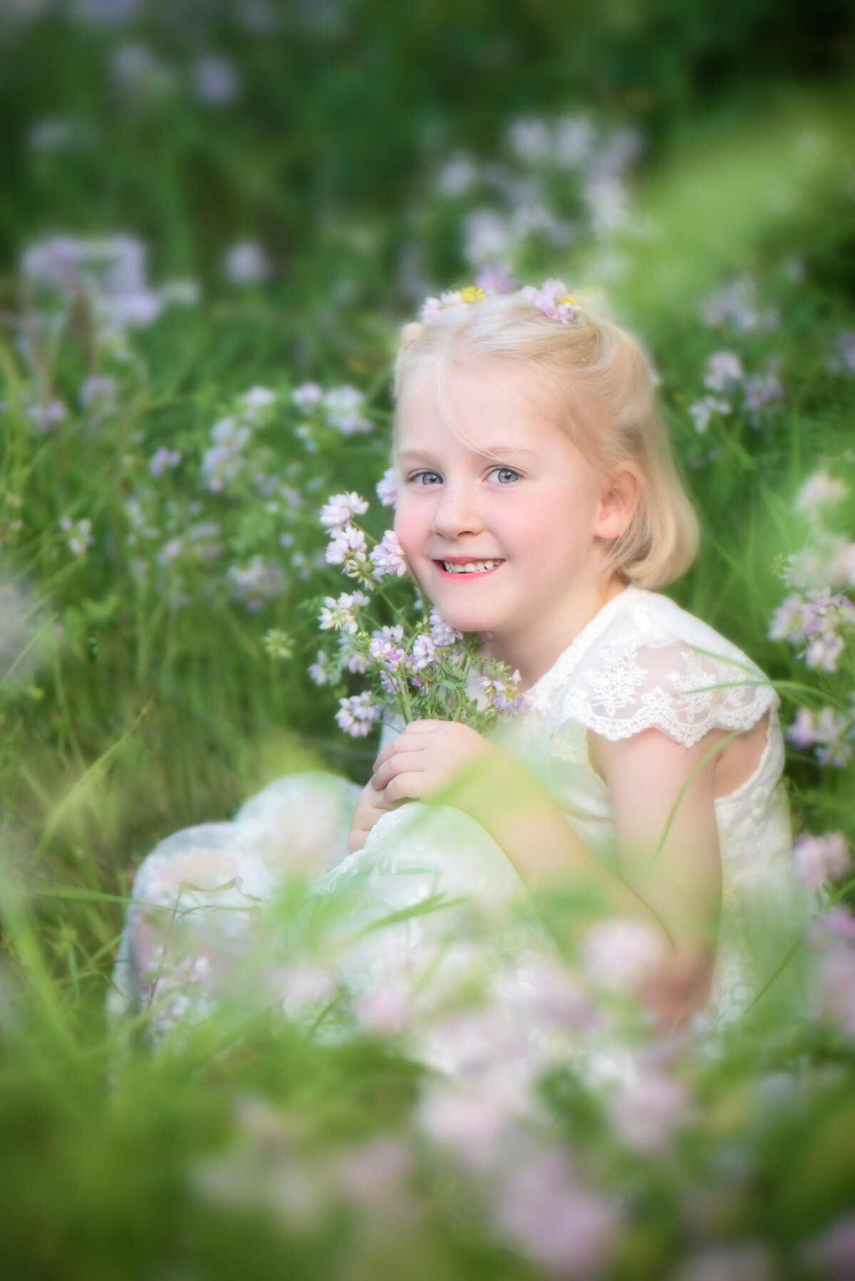 Charming portrait of a young girl surrounded by a lush wildflower meadow, dressed in a soft pastel gown. Captured in Overland Park, Kansas, this natural and serene setup is perfect for families seeking whimsical child photography in the Kansas City area.