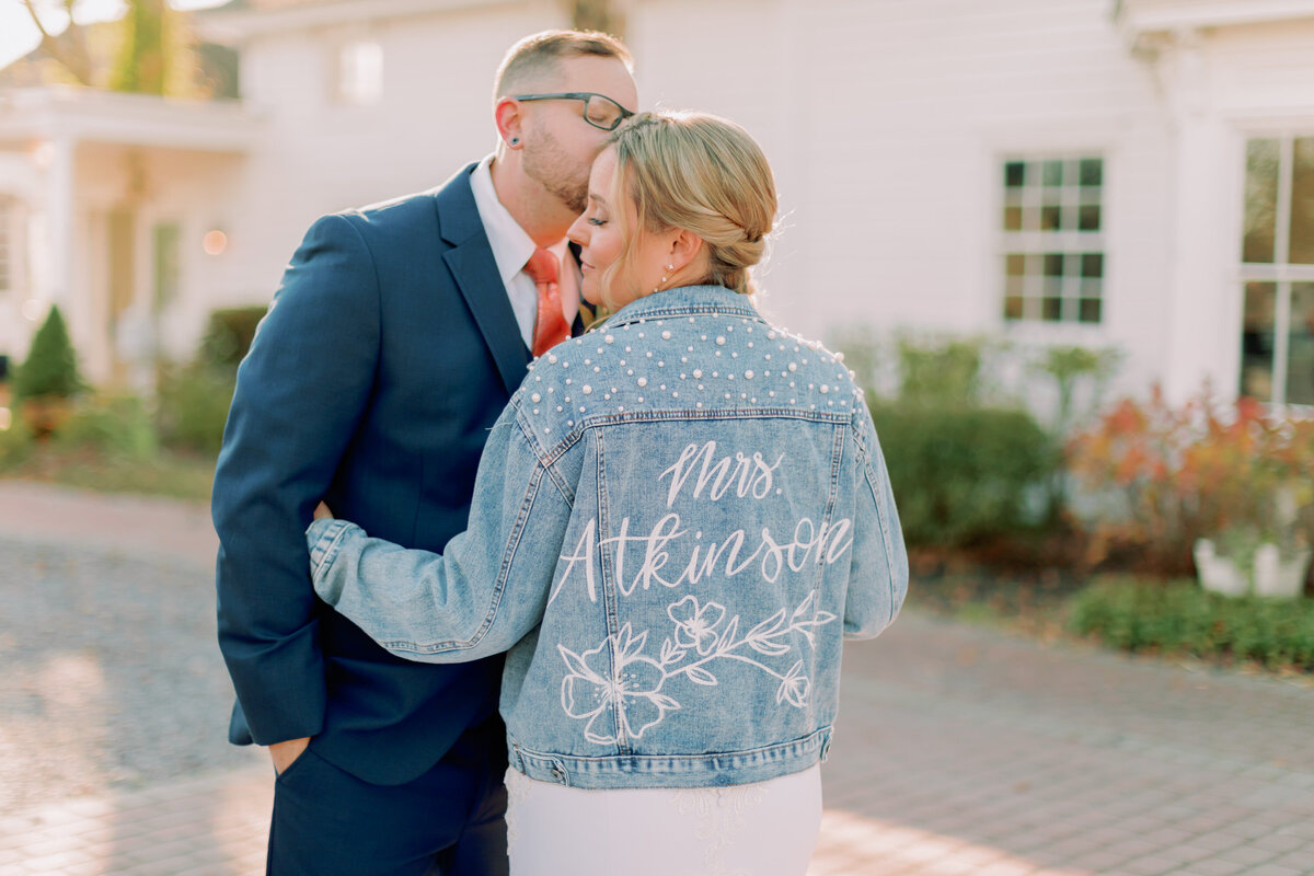 A newlywed hugging their partner as they wear a denim jacket 