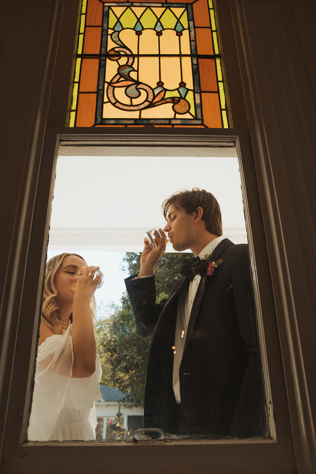 Bride and groom taking a drink through the window on their wedding day