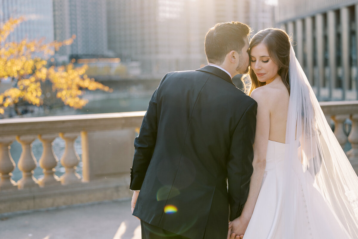 Bride and groom sharing an intimate moment by the river near the Blackstone Hotel, planned by Chicago wedding planner Savoir Fête. The sunlight creates a magical scene.