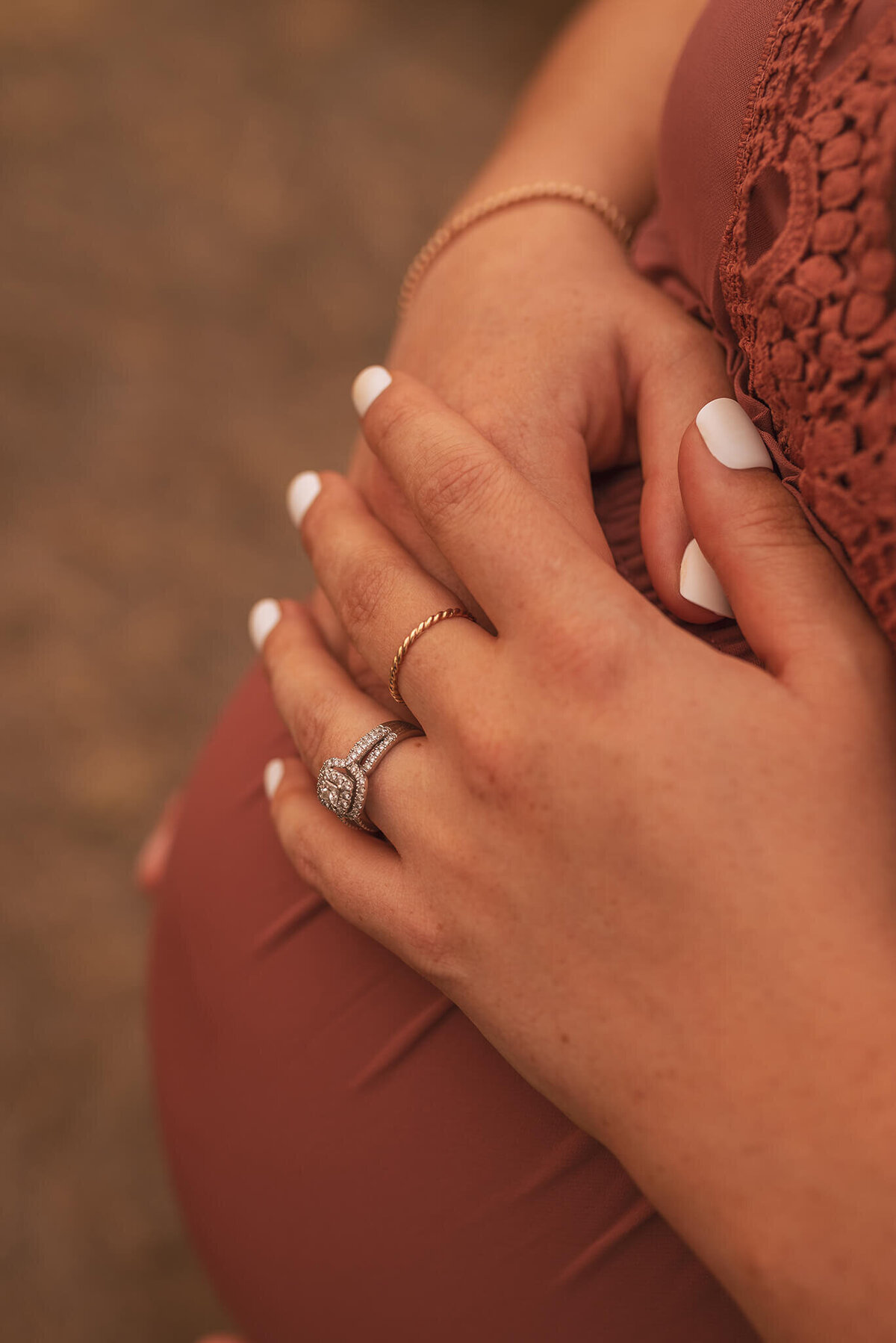 An up close shot of a woman hands on top of her pregnant belly. She had a gorgeous engagement ring. Captured by Brittany Danielle