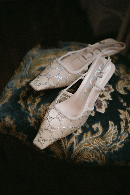Escarpins de la mariée posés sur un coussin. Photographie de mariage vintage.