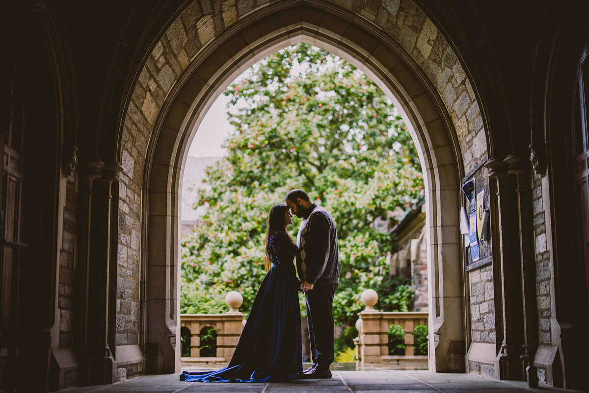 A couple standing under an arch and sharing a moment together at princeton university in nj