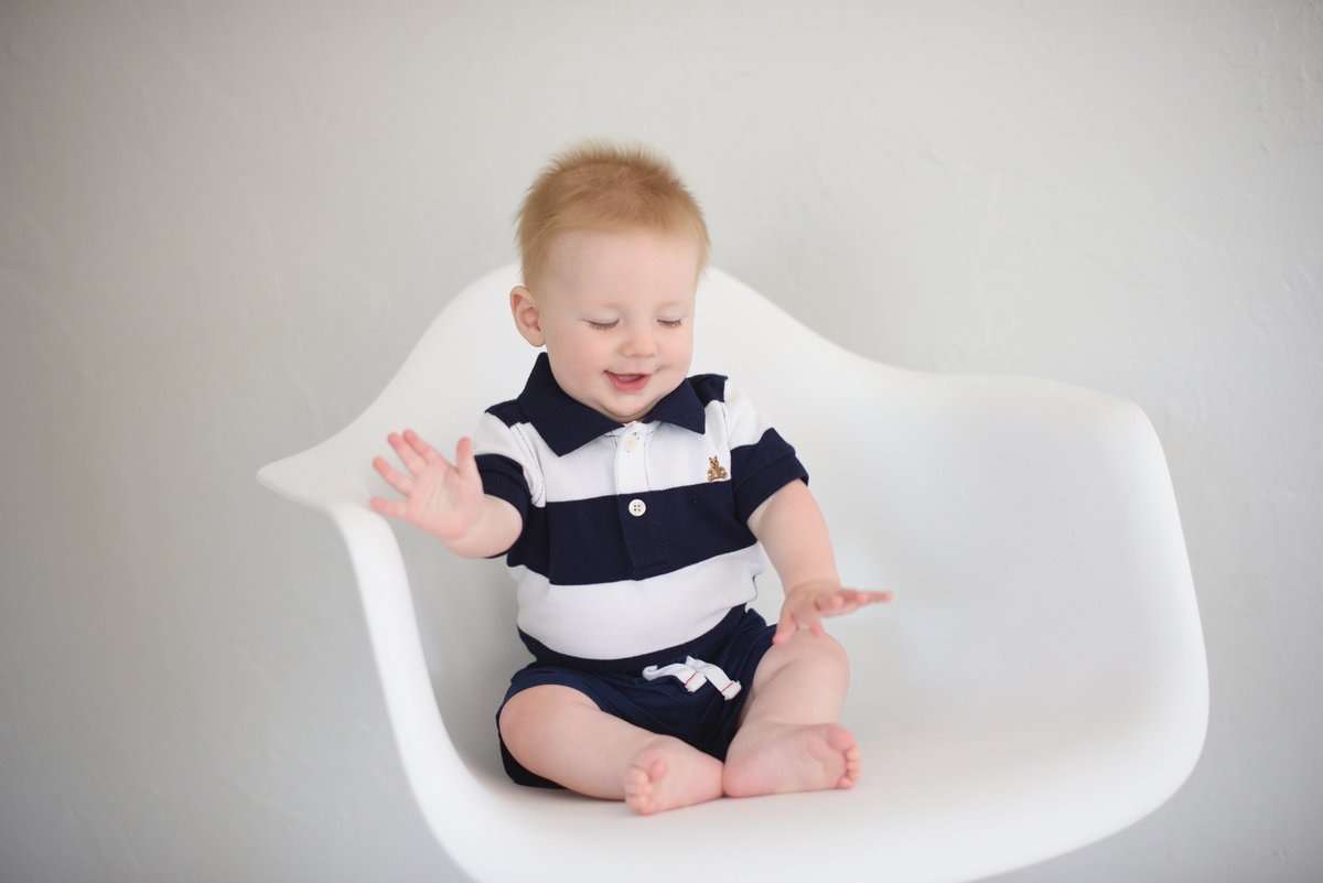Baby sitting a chair laughing in portrait studio in Boise.