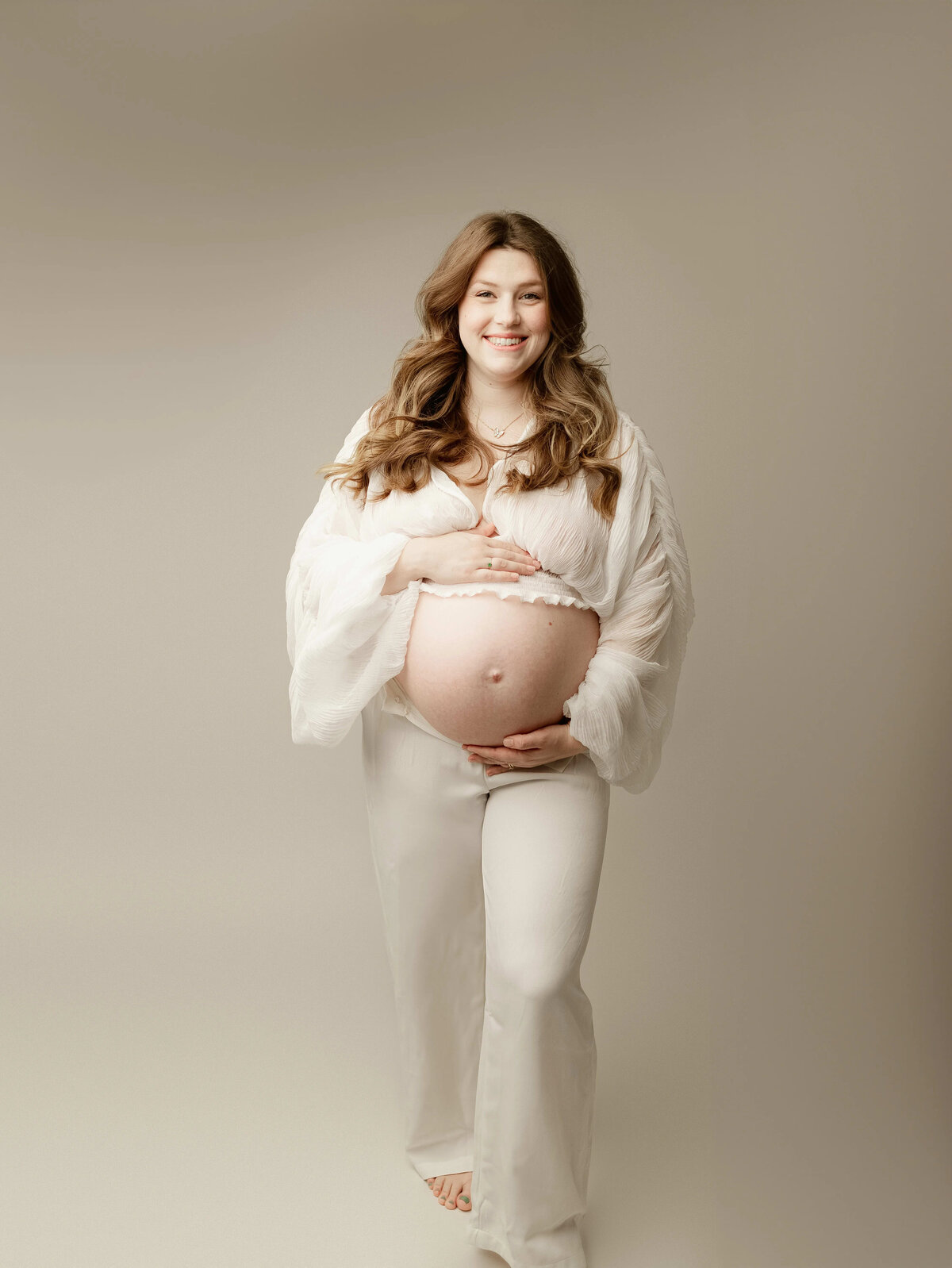 Studio maternity session with white flowy pants and sheer white top