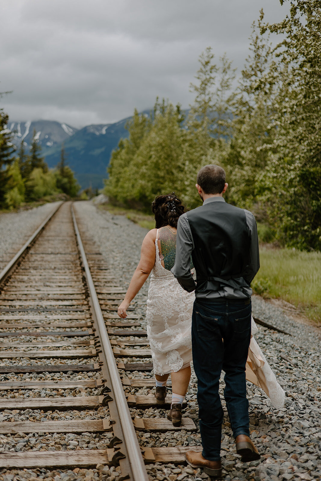 Elopement couple walks on Alaska train tracks.