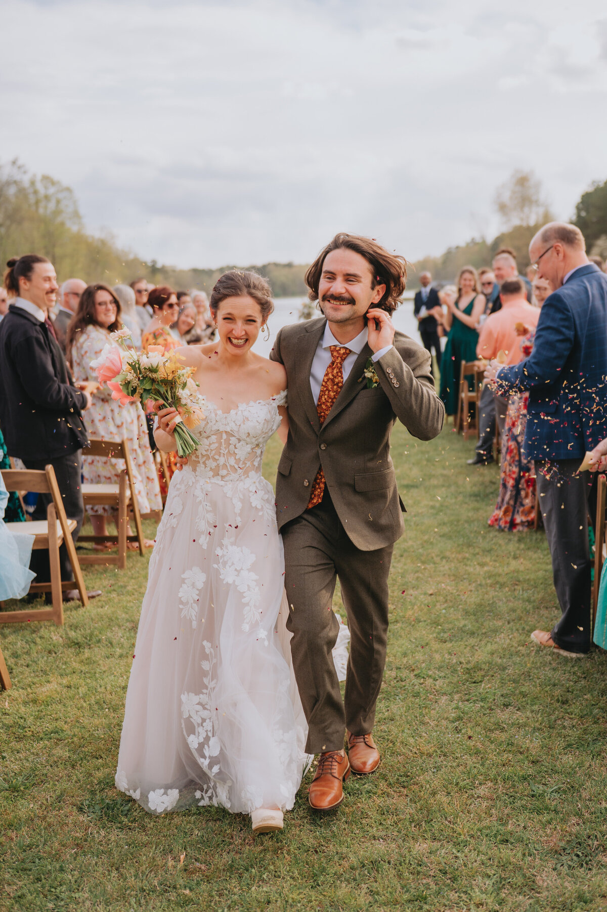 Newlyweds walk down an aisle while smiling