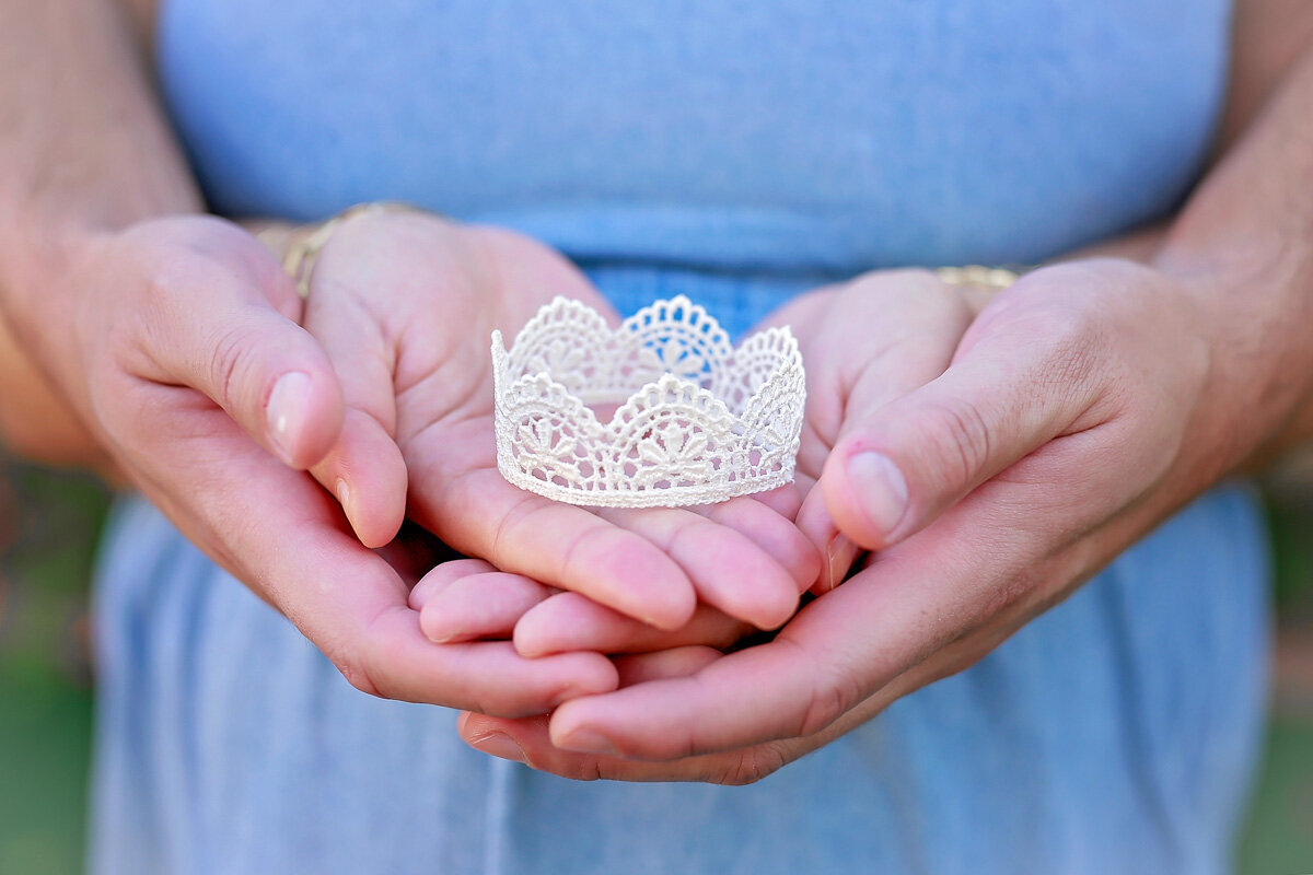 Young parents hands holding a baby girl crown for gender reveal photo session in Calgary Alberta