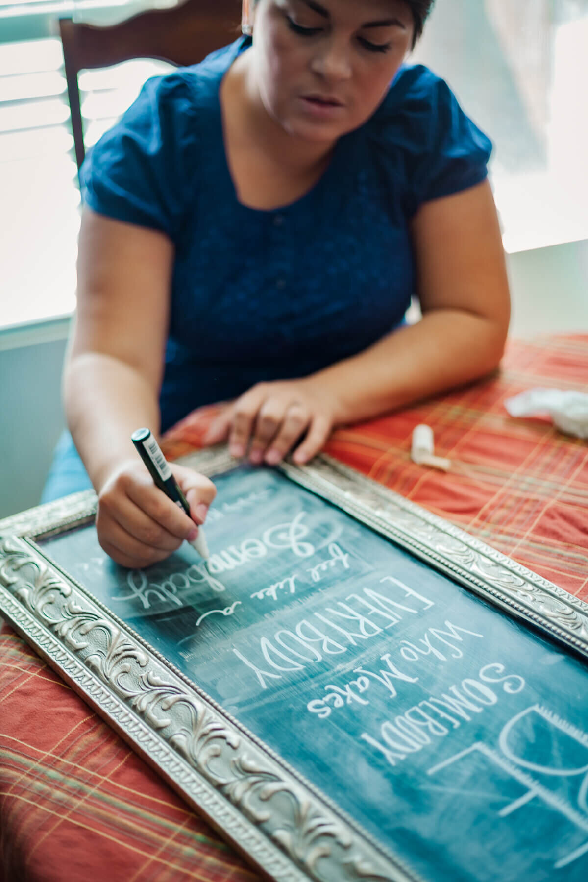 A woman writes on a decorative chalk board.