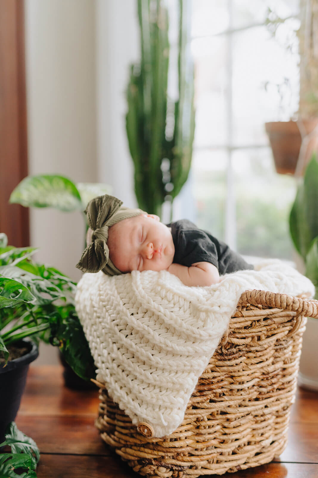Baby wearing green headband asleep in a moses basket