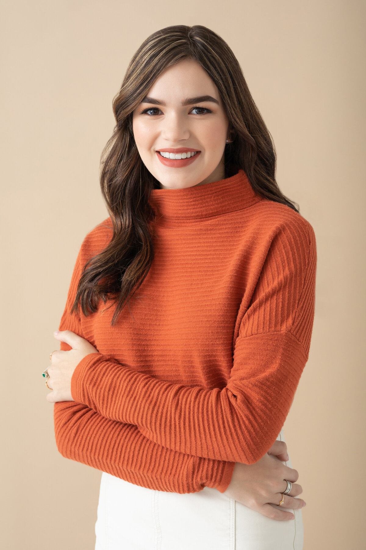 A girl in an orange sweater with her arms crossed