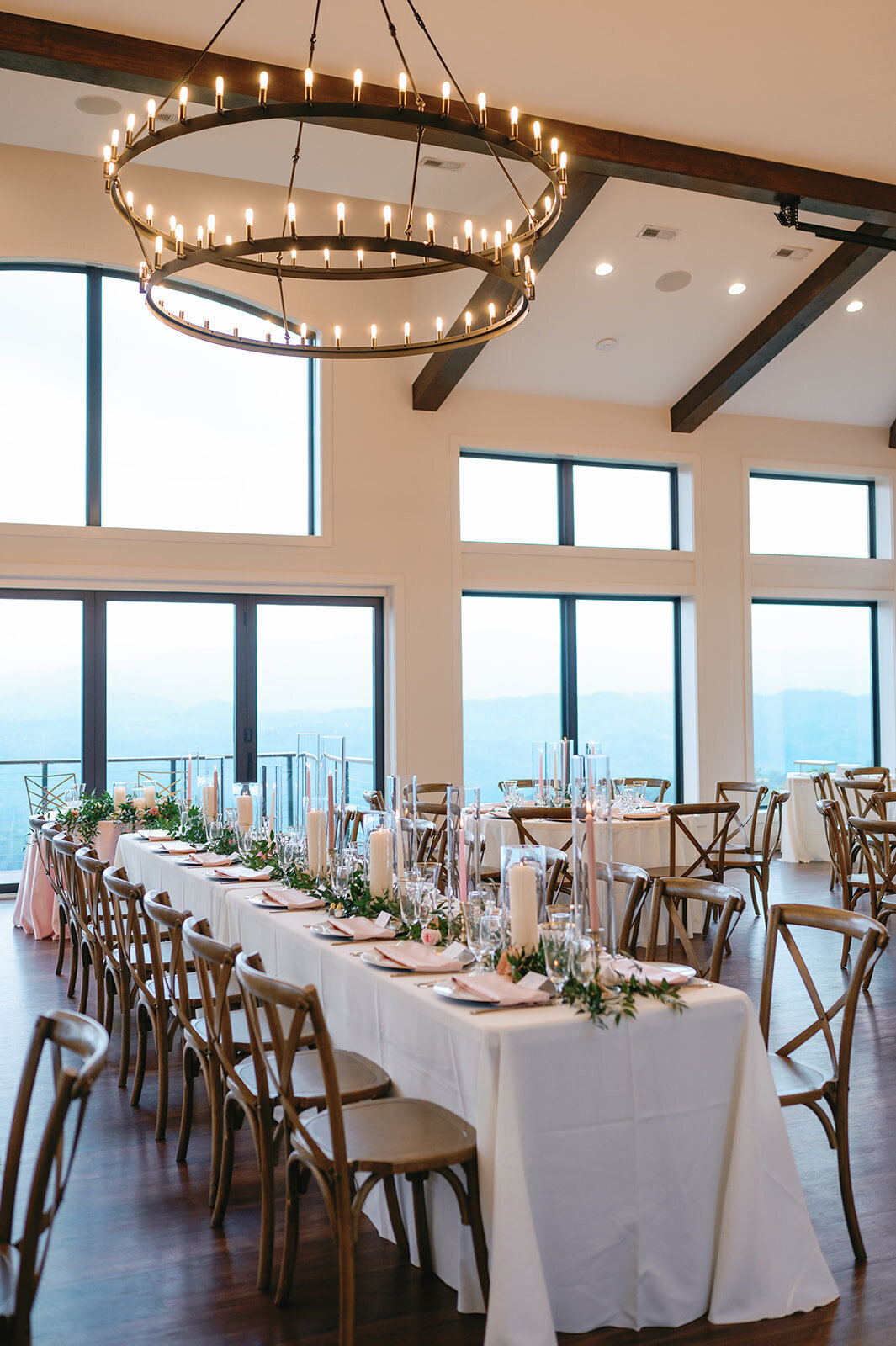 Long farm tables covered in white linens with candles and flowers
