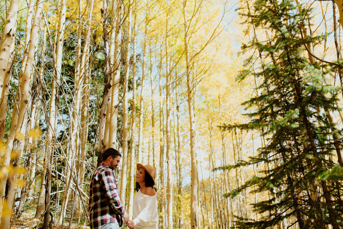 couple photographed among tall wooded trees in Aspen Colorado