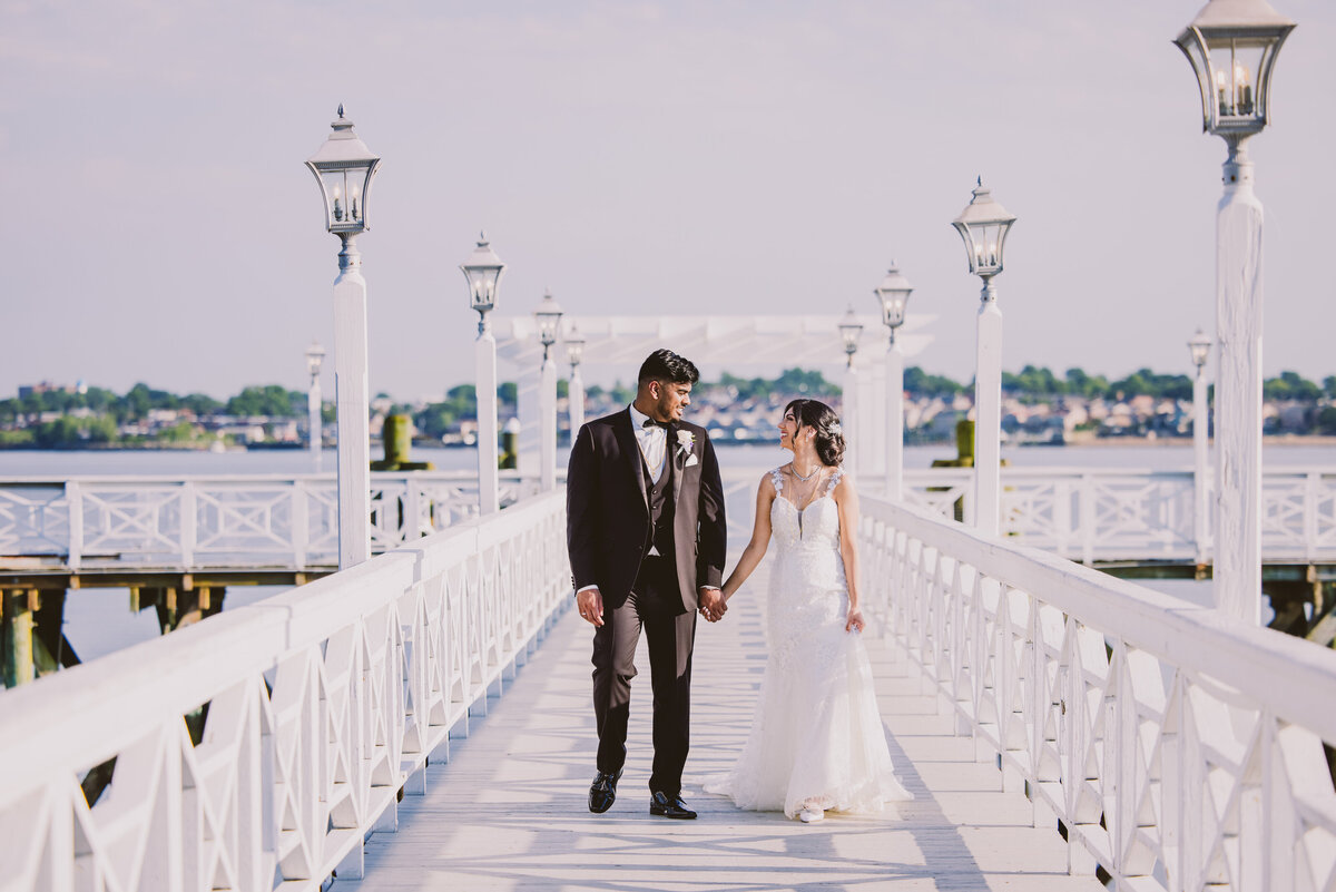 Indian christian bride and groom walking down a white pier at marina del rey in the bronx